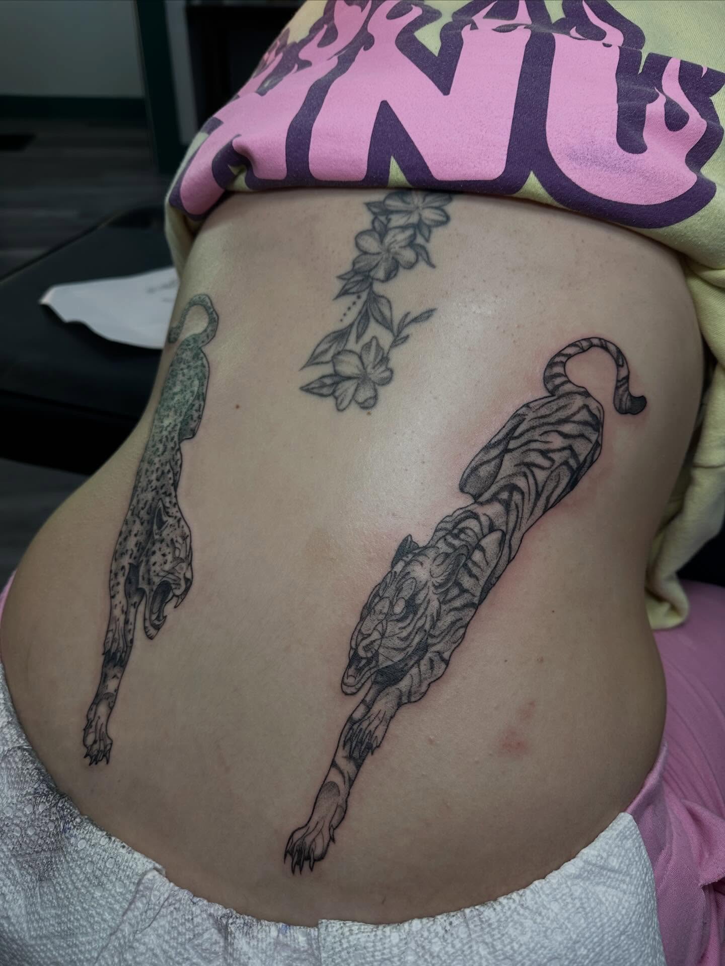 Tiger and leopard black and grey tattoo on the torso by Maddie Neibert