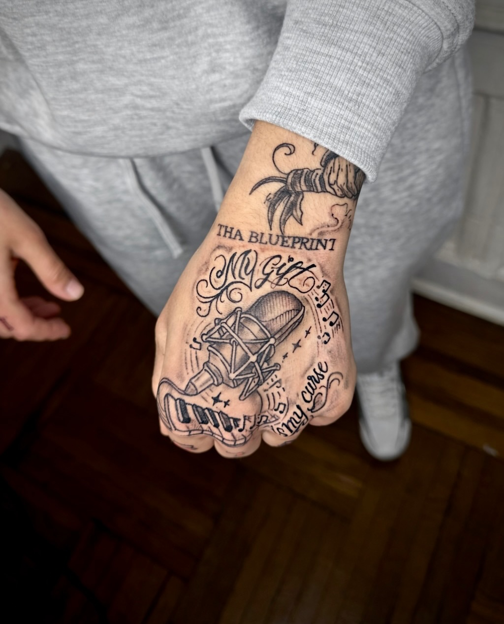 Microphone and piano keys black and grey tattoo on the hand by JayyeSosa