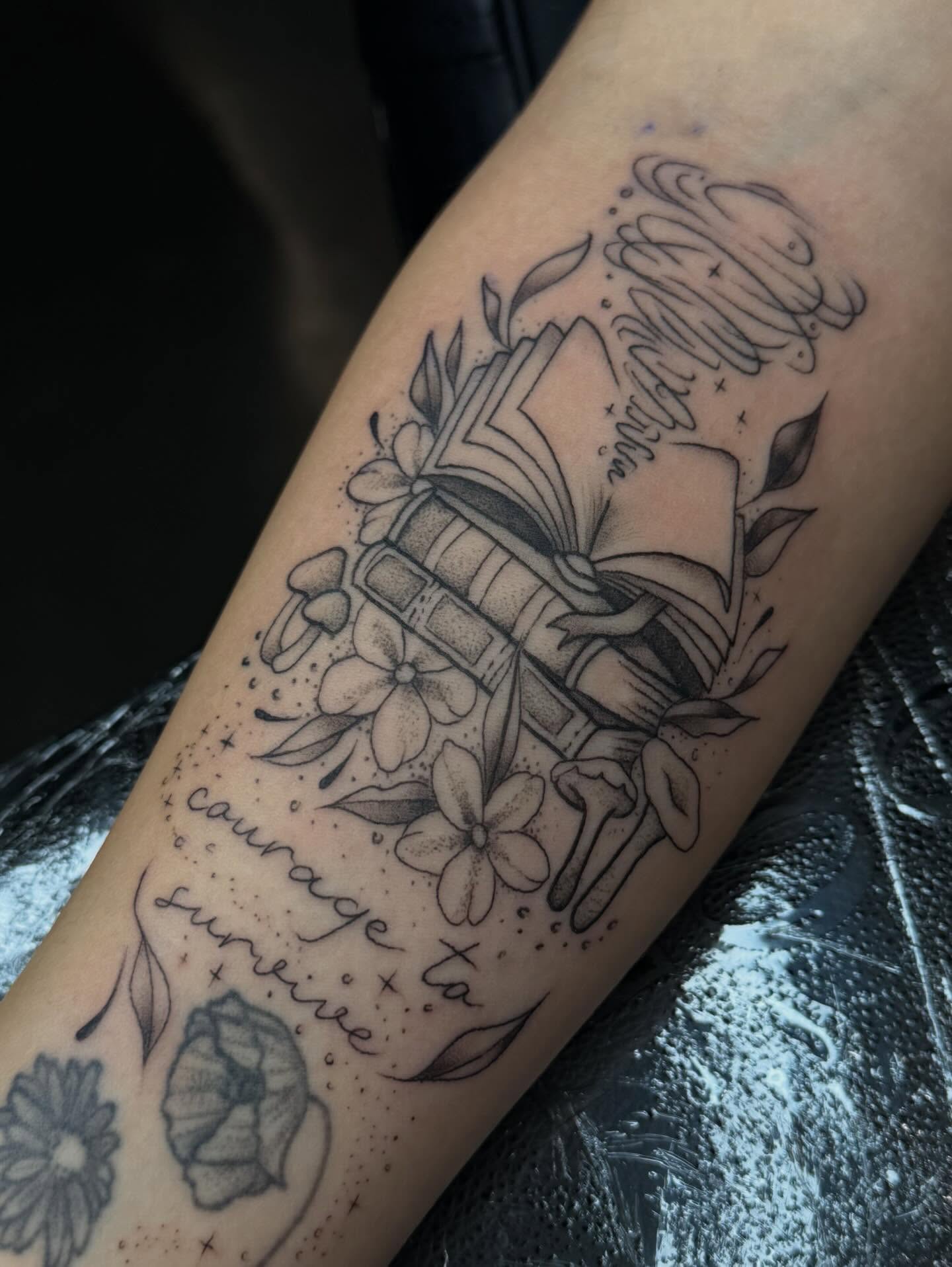 Book and flowers black and grey tattoo on the forearm by Susie Maj