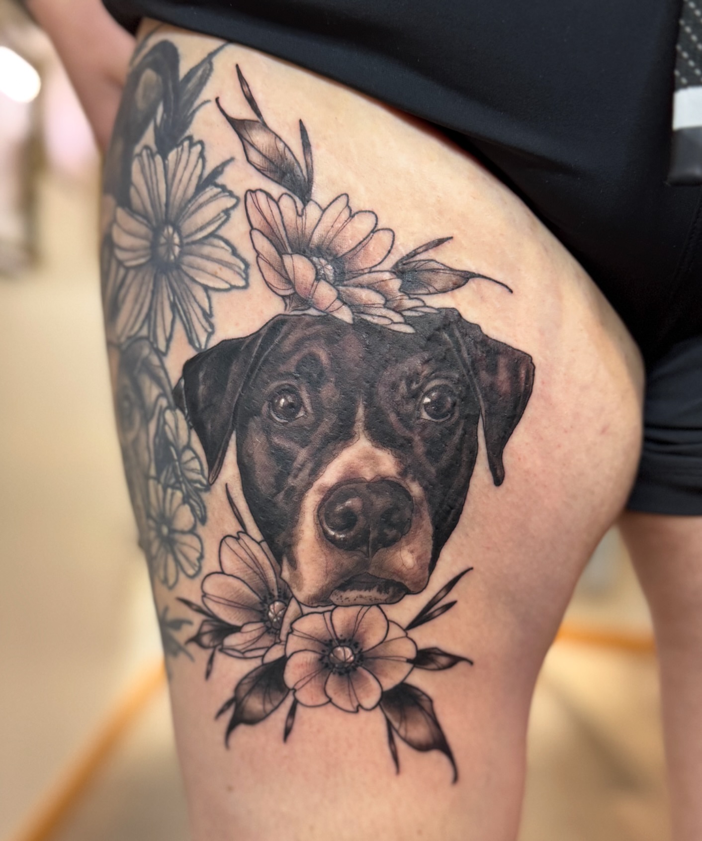 Dog with flowers realism tattoo on the thigh by Erin Bratzler