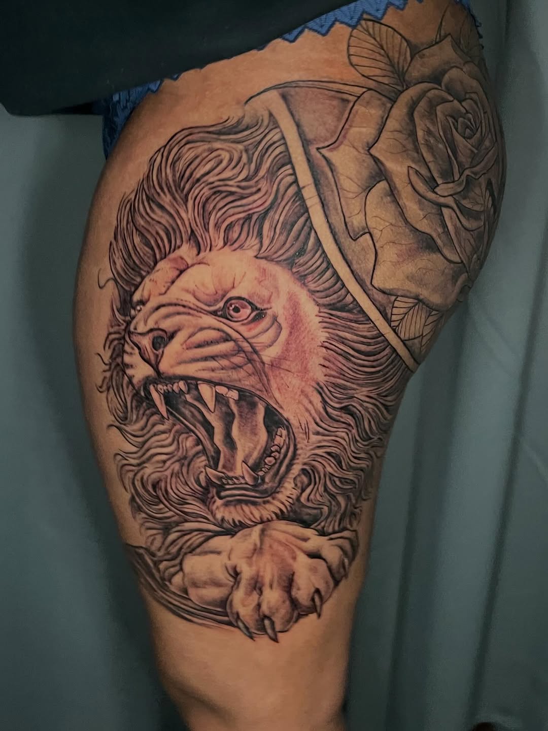 Roaring lion and rose realism tattoo on the thigh by Jakobi