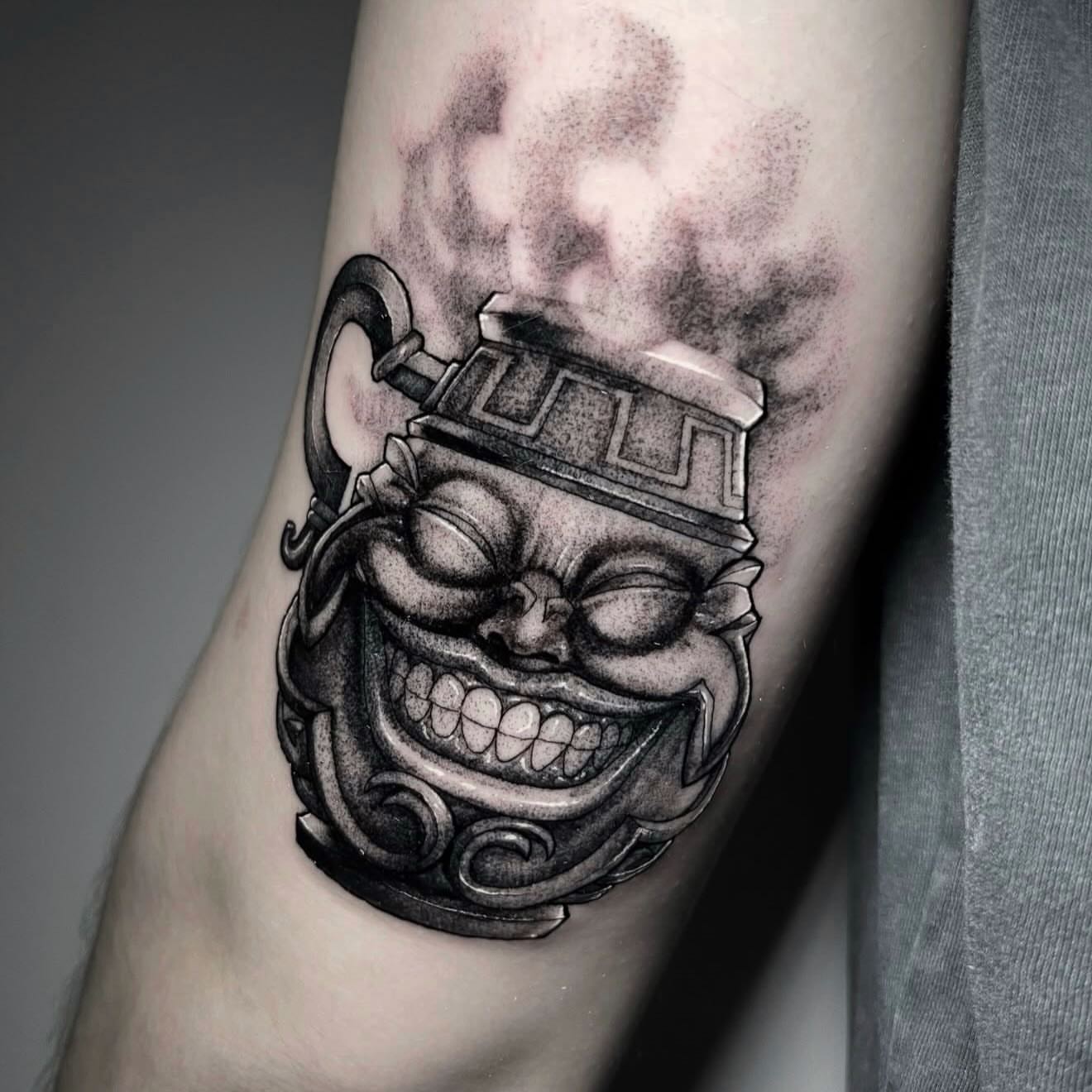 Smiling mask black and grey tattoo on the forearm by Xavi Xiva TATTOO
