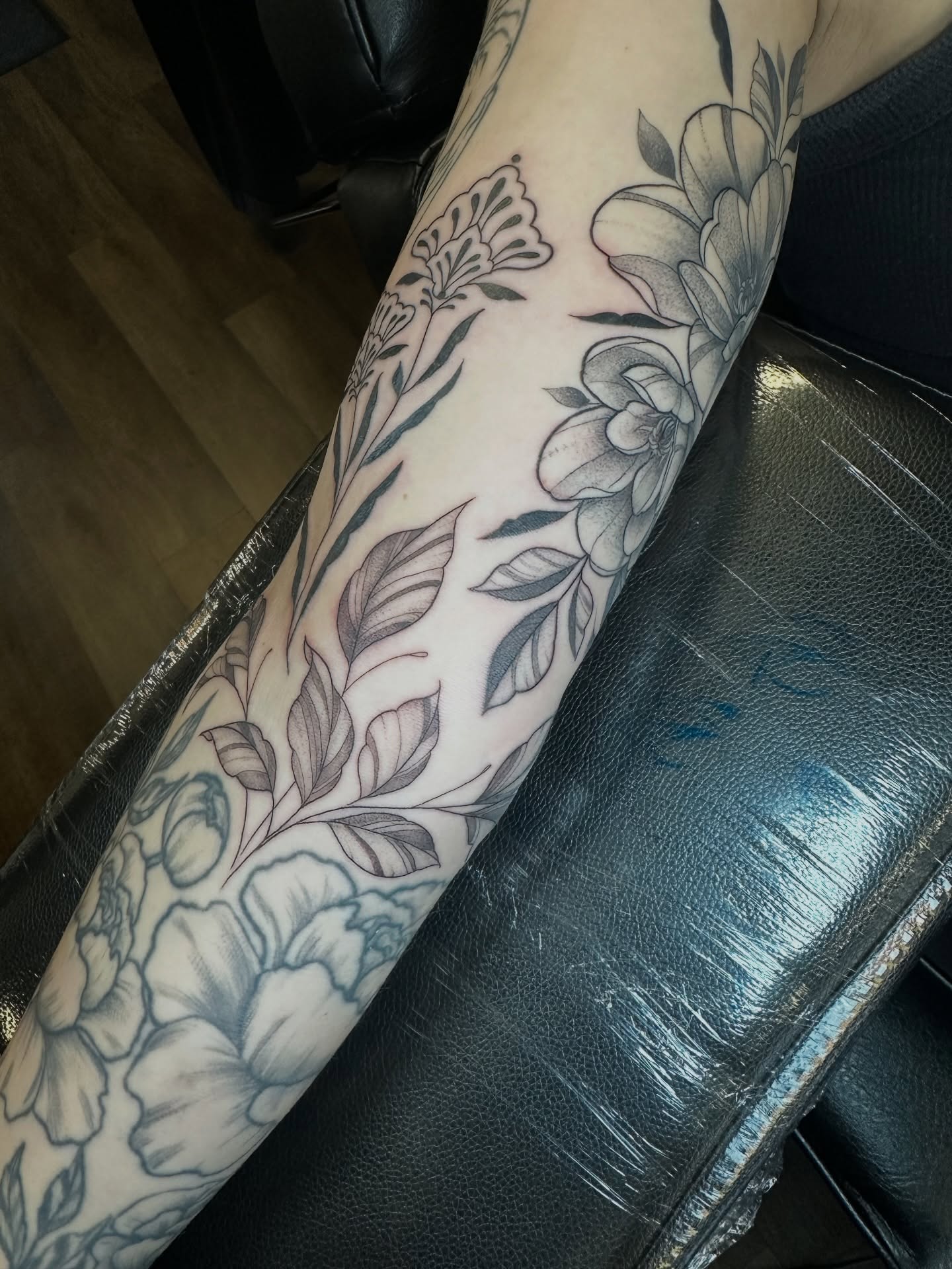 Floral arrangement black and grey tattoo on the forearm by Priscilla Michels