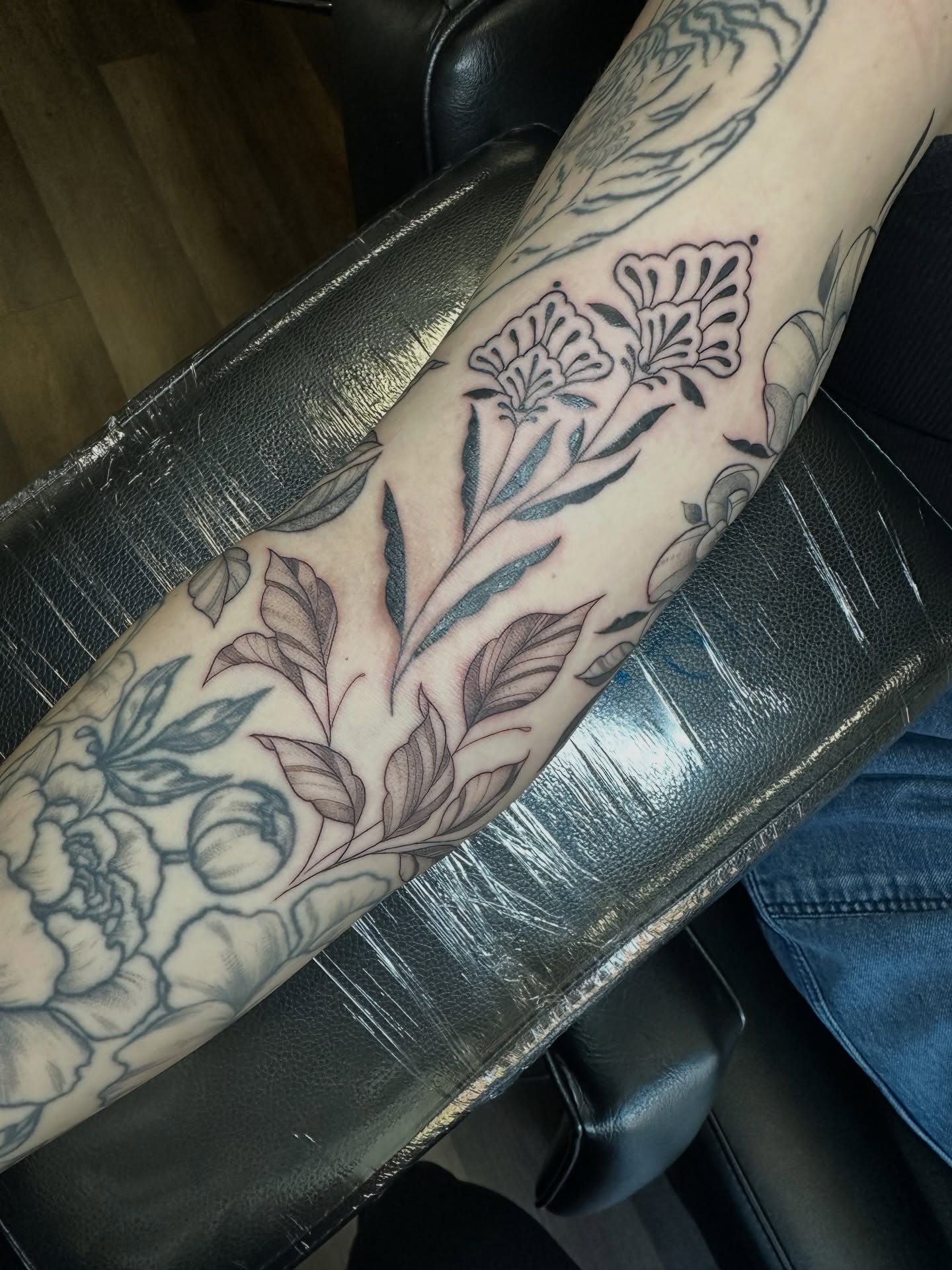 Floral arrangement black and grey tattoo on the forearm by Priscilla Michels