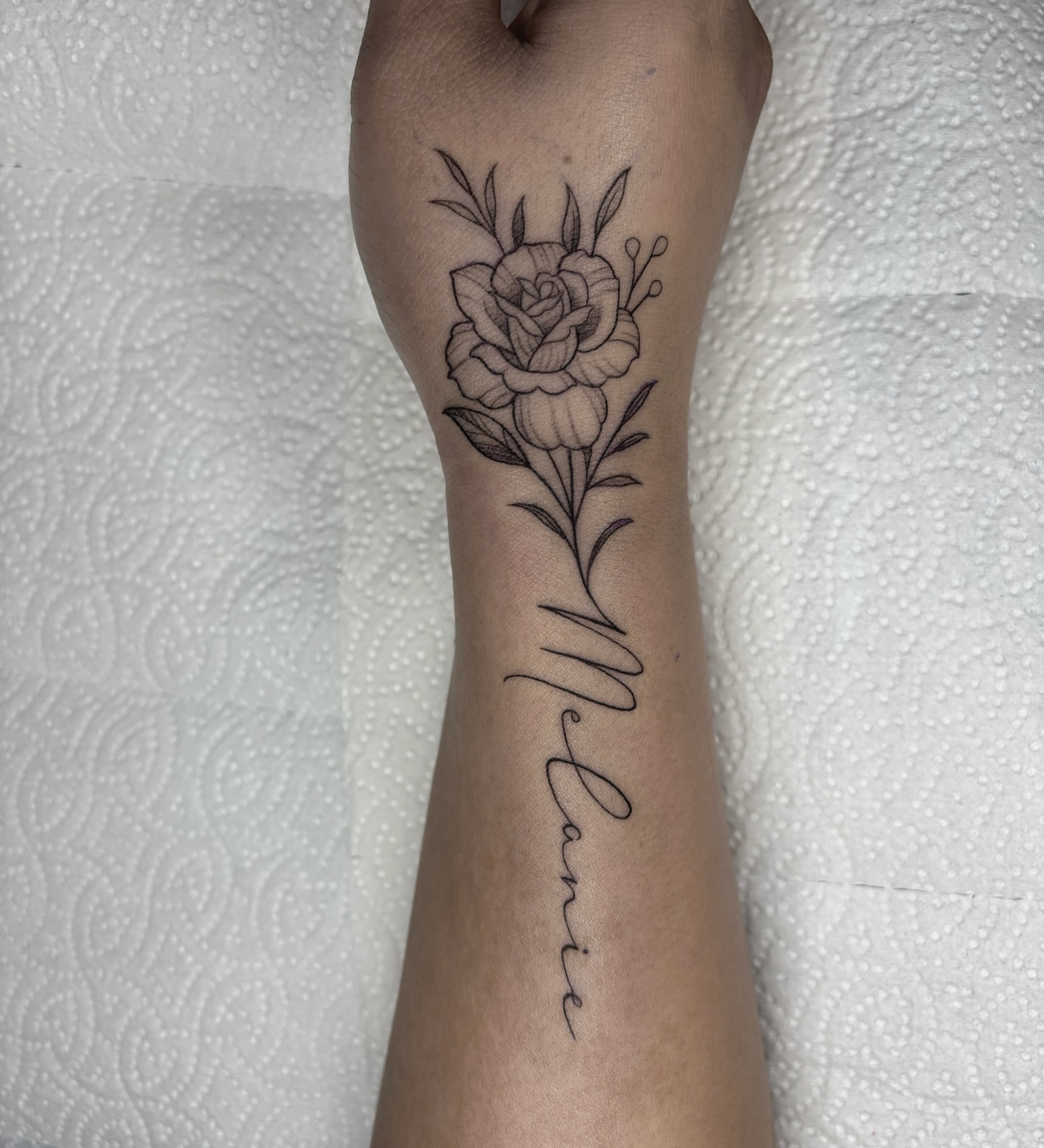 Rose and name black and grey tattoo on the forearm by Fineline tattoos by Kinsey