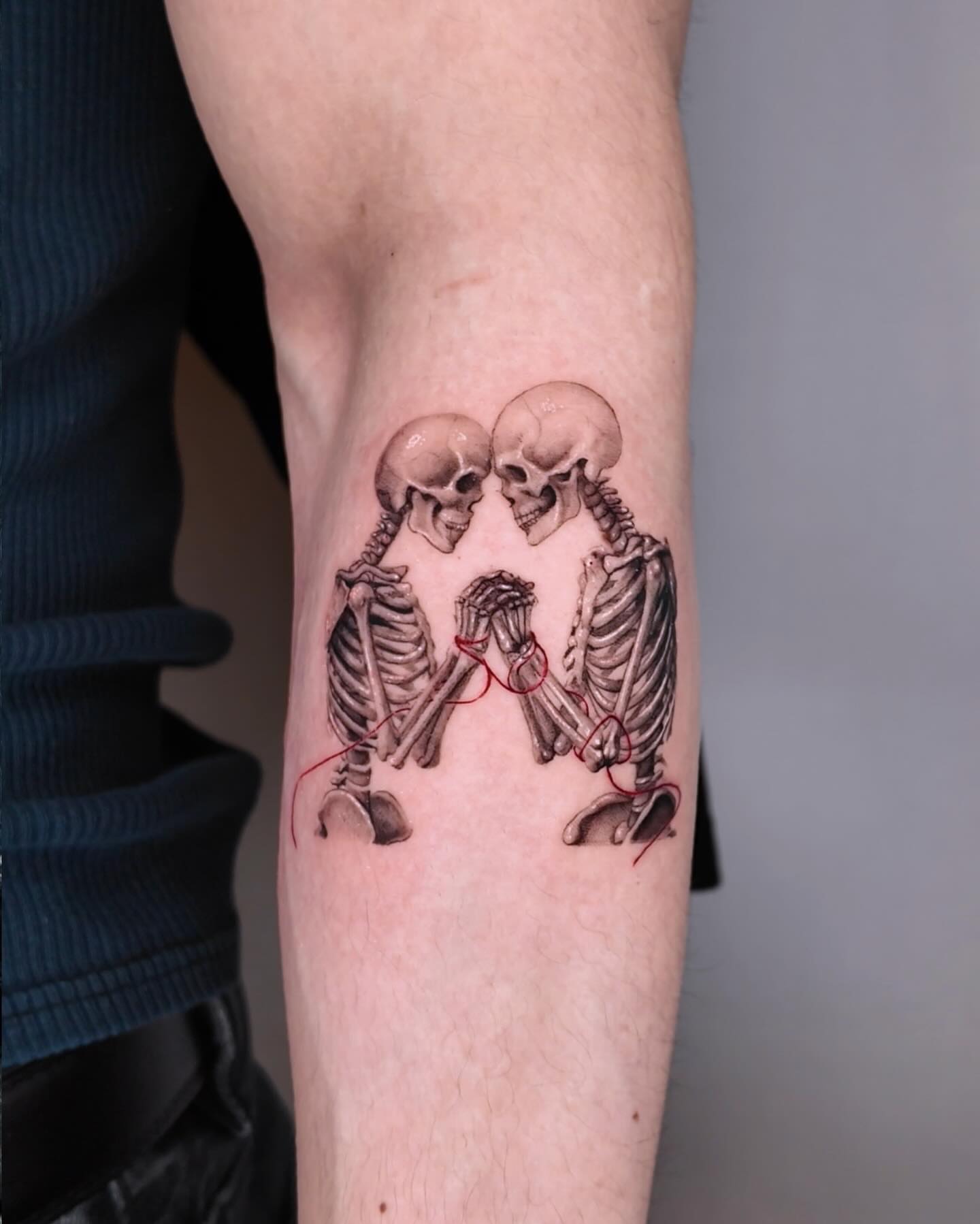 Skeletons kissing realism tattoo on the forearm by Gabriel