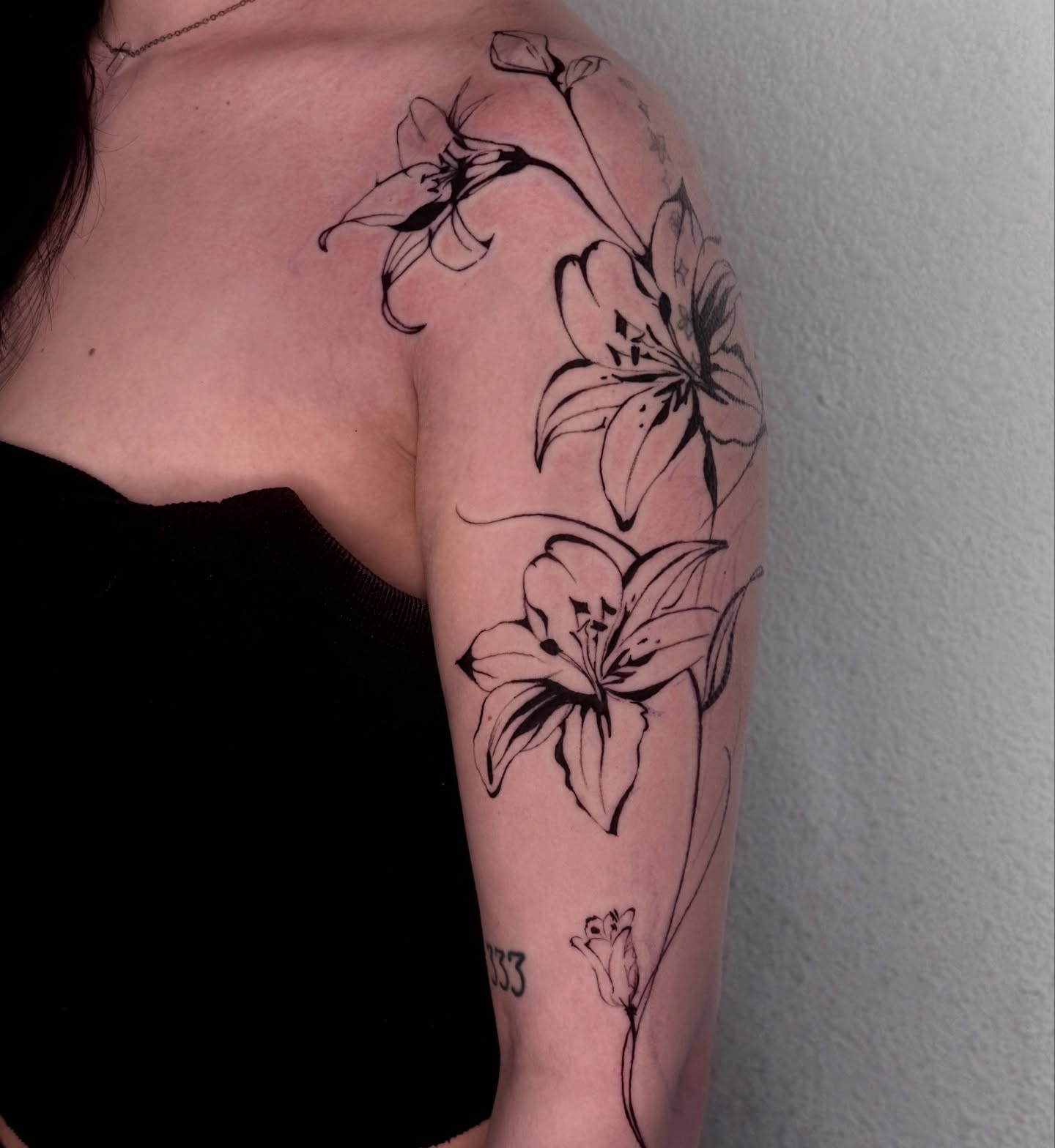 Lilies black and grey tattoo on the upper arm by josselyn ☪︎