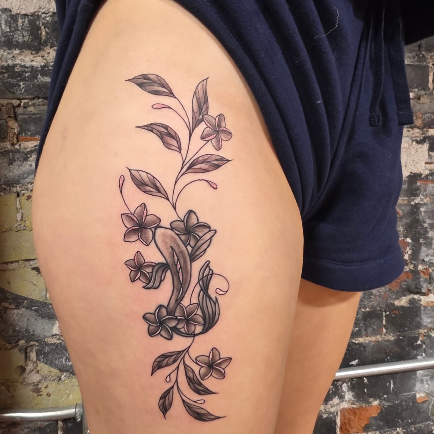 Floral arrangement black and grey tattoo on the thigh by Tattoos by Annie