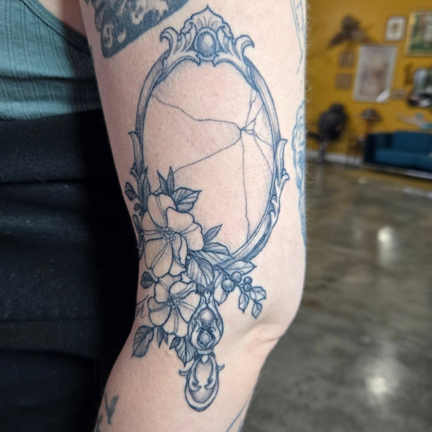 Mirror with floral decoration black and grey tattoo on the forearm by Amanda Hinrichs