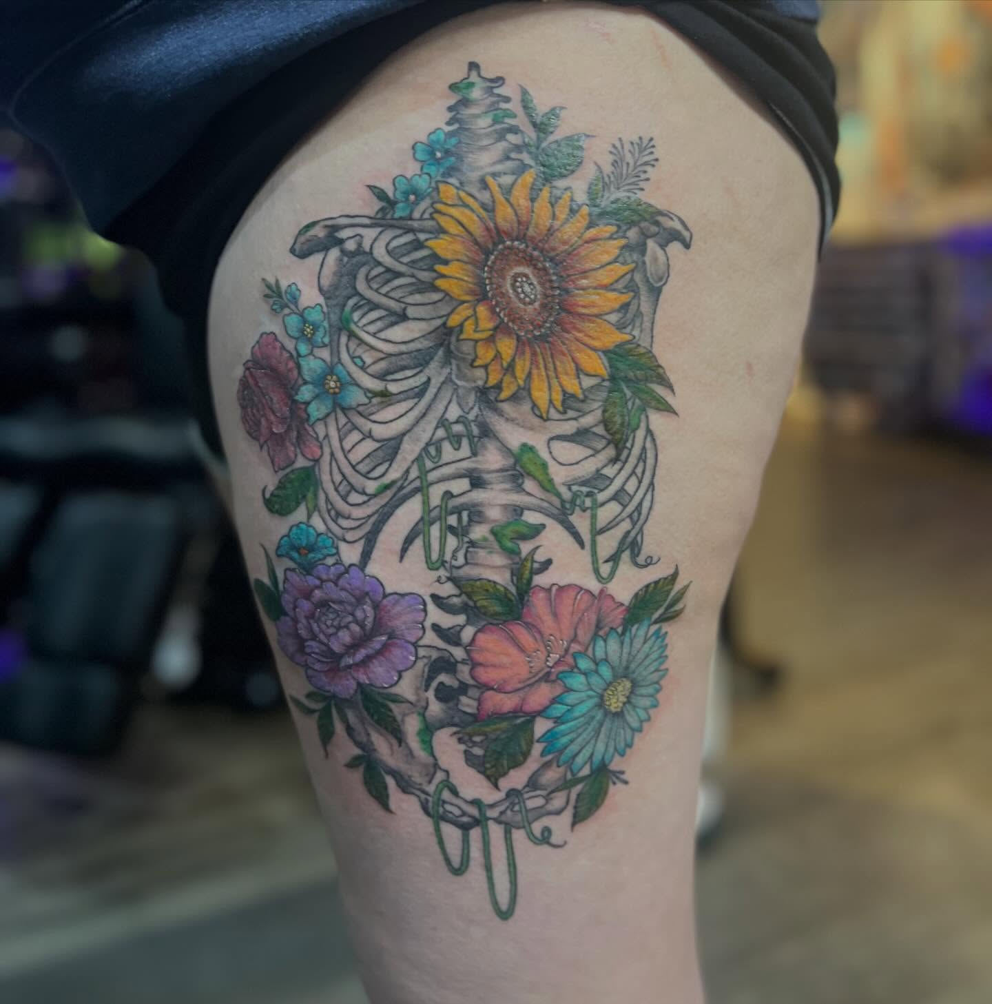 Skeleton with flowers new school tattoo on the thigh by Rikki