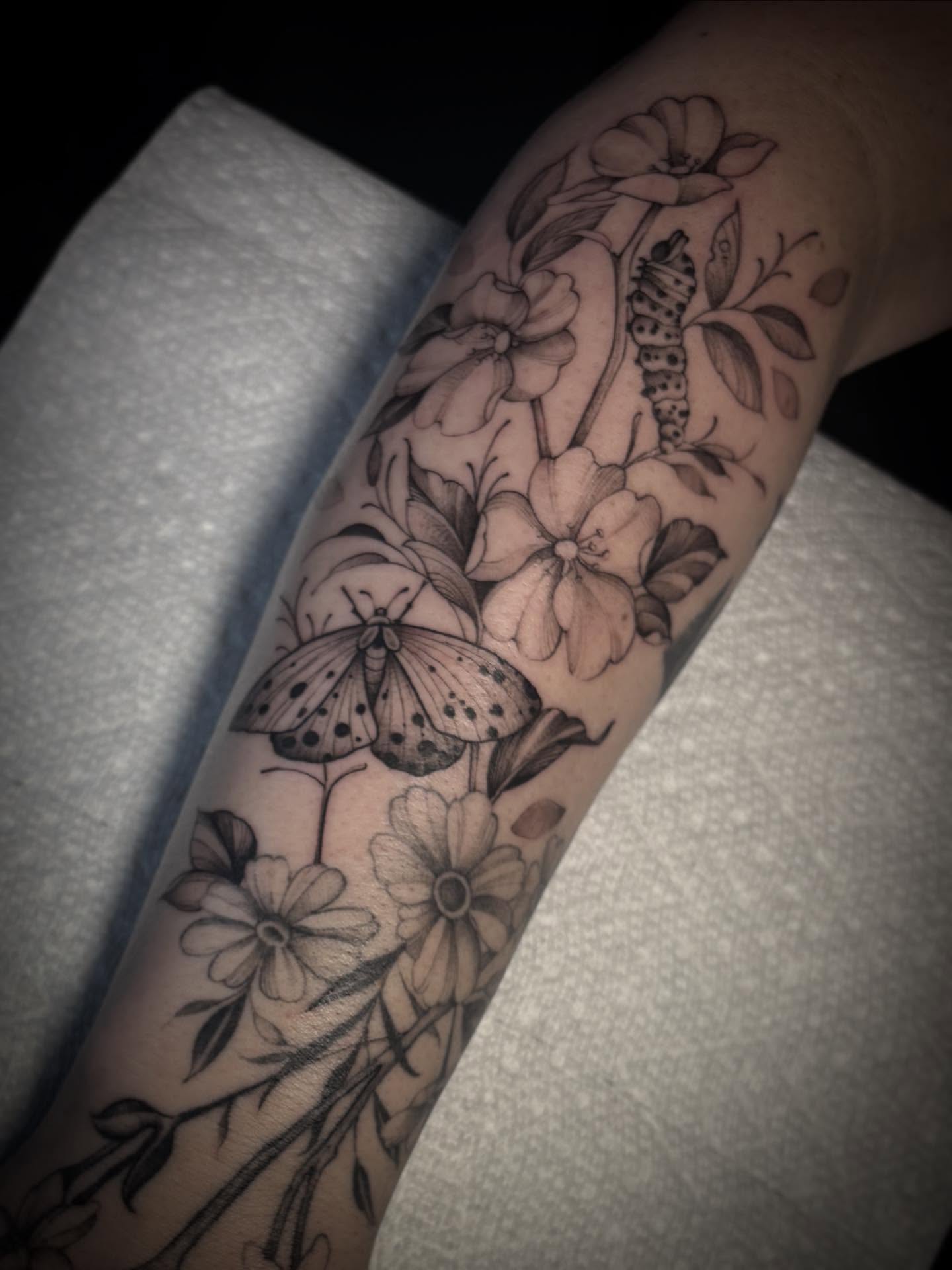 Butterfly and flowers black and grey tattoo on the forearm by Lena Lawrence
