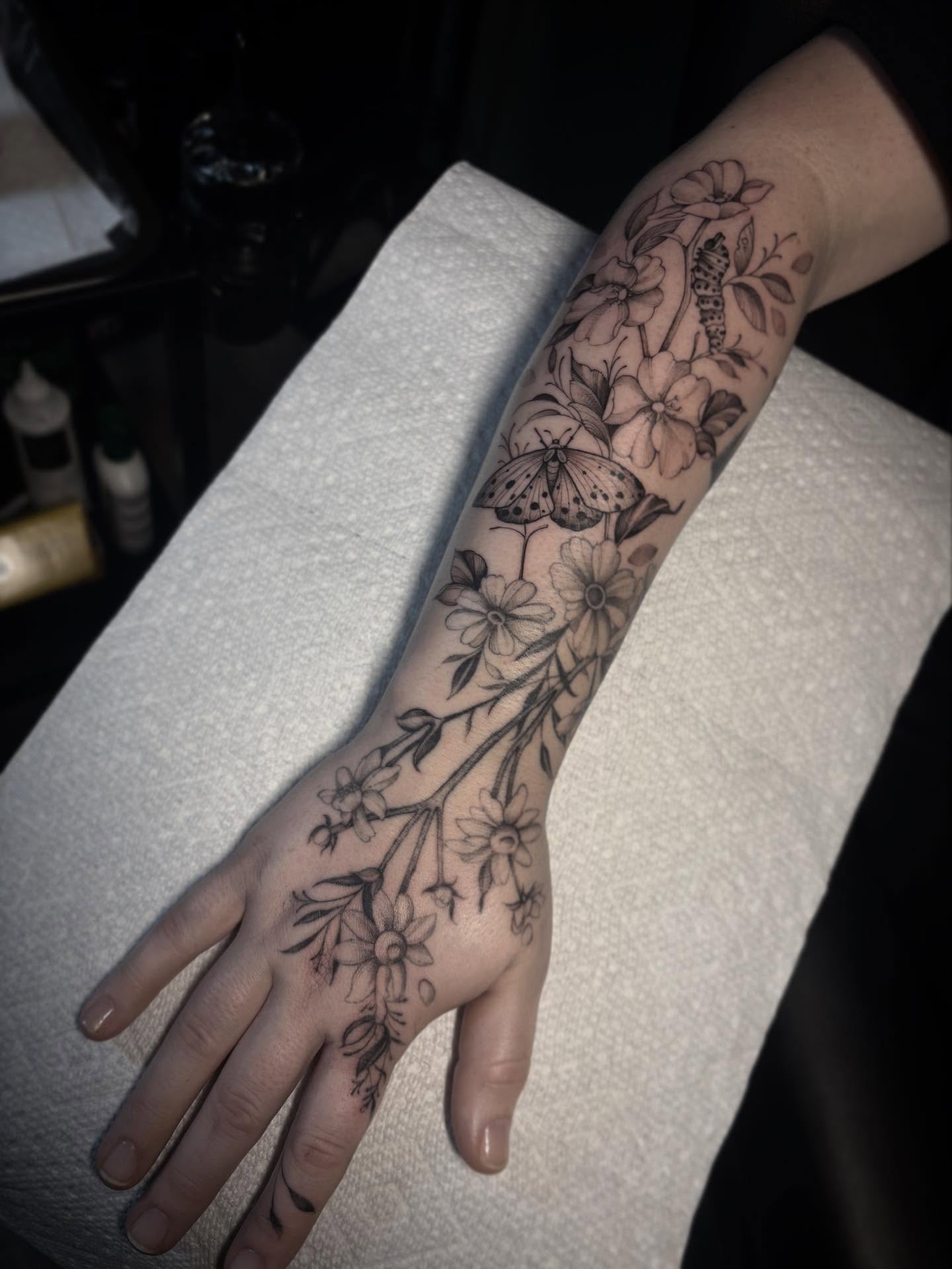 Flower branch with butterfly realism tattoo on the forearm by Lena Lawrence