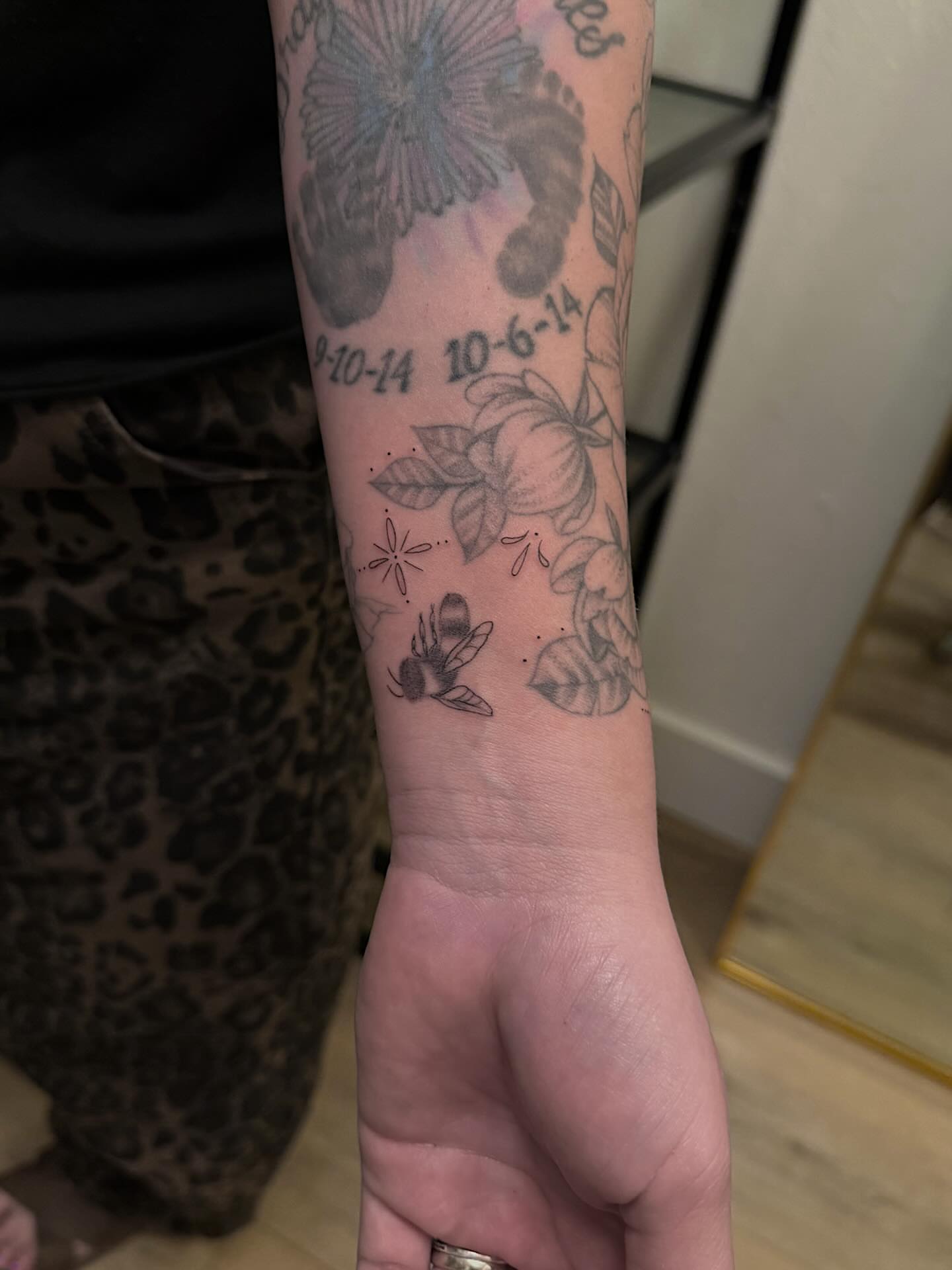 Flower and footprints black and grey tattoo on the forearm by Shelby Lynn Bayles, Ogden, Utah