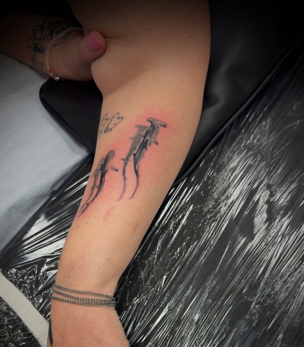 Dolphins black and grey tattoo on the forearm by Julian Olson