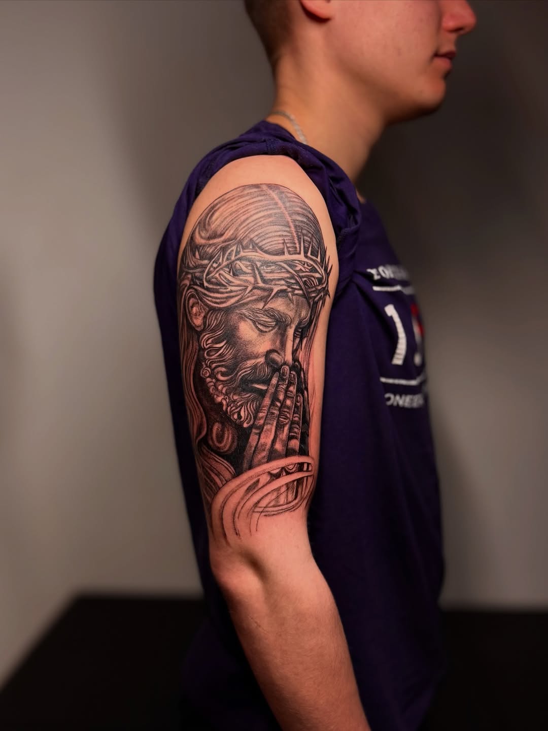 Jesus Christ praying Chicano tattoo on the upper arm by Виктория Лукьянова