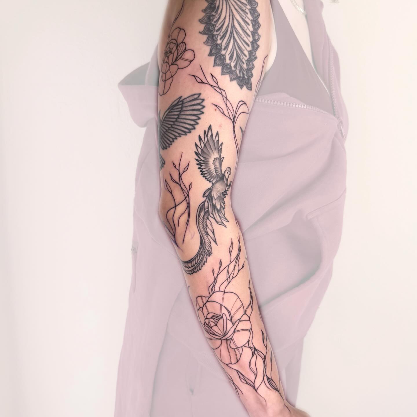 Bird and floral black and grey tattoo on the forearm by Nika