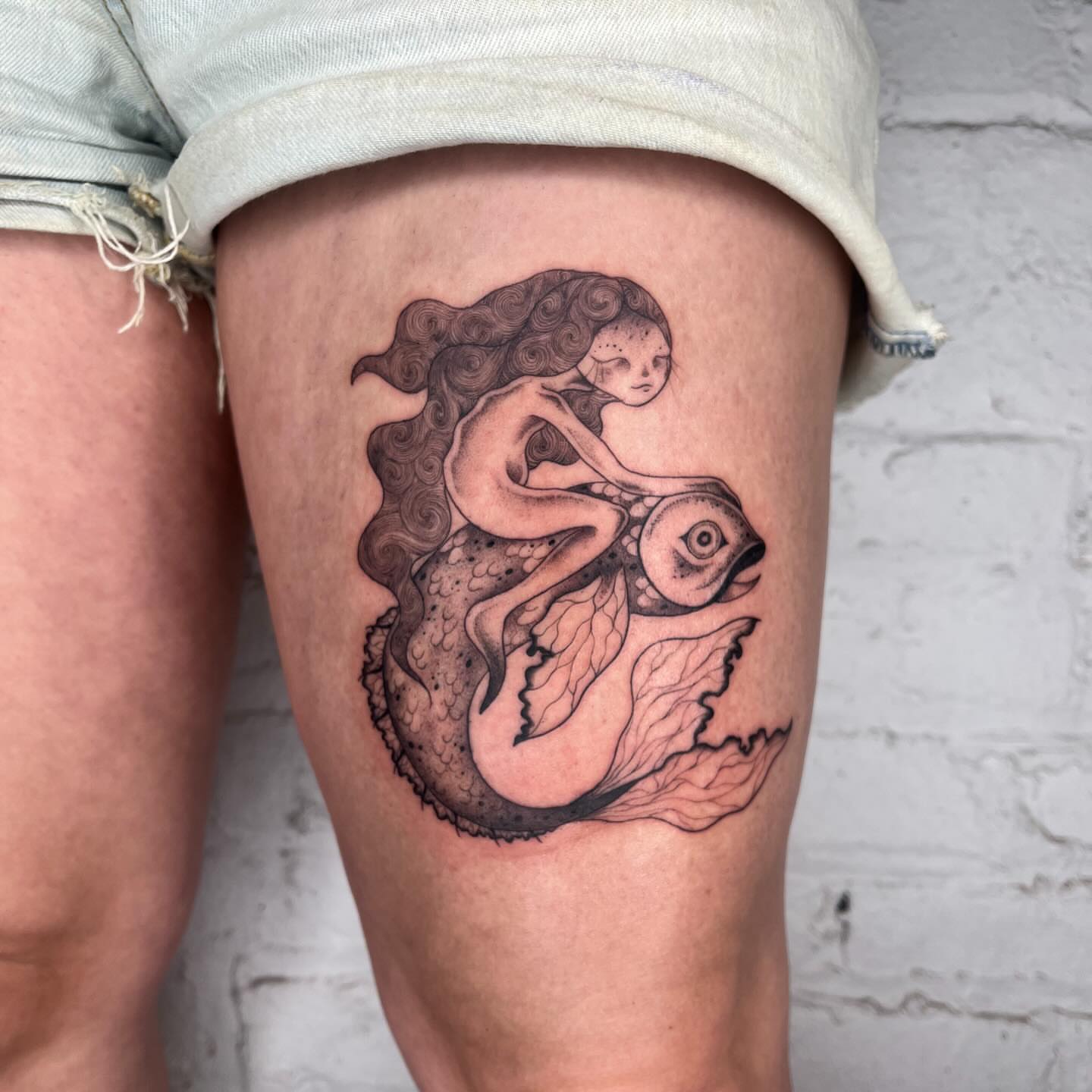Mermaid and fish realism tattoo on the thigh by 𝔇𝔢𝔰𝔦