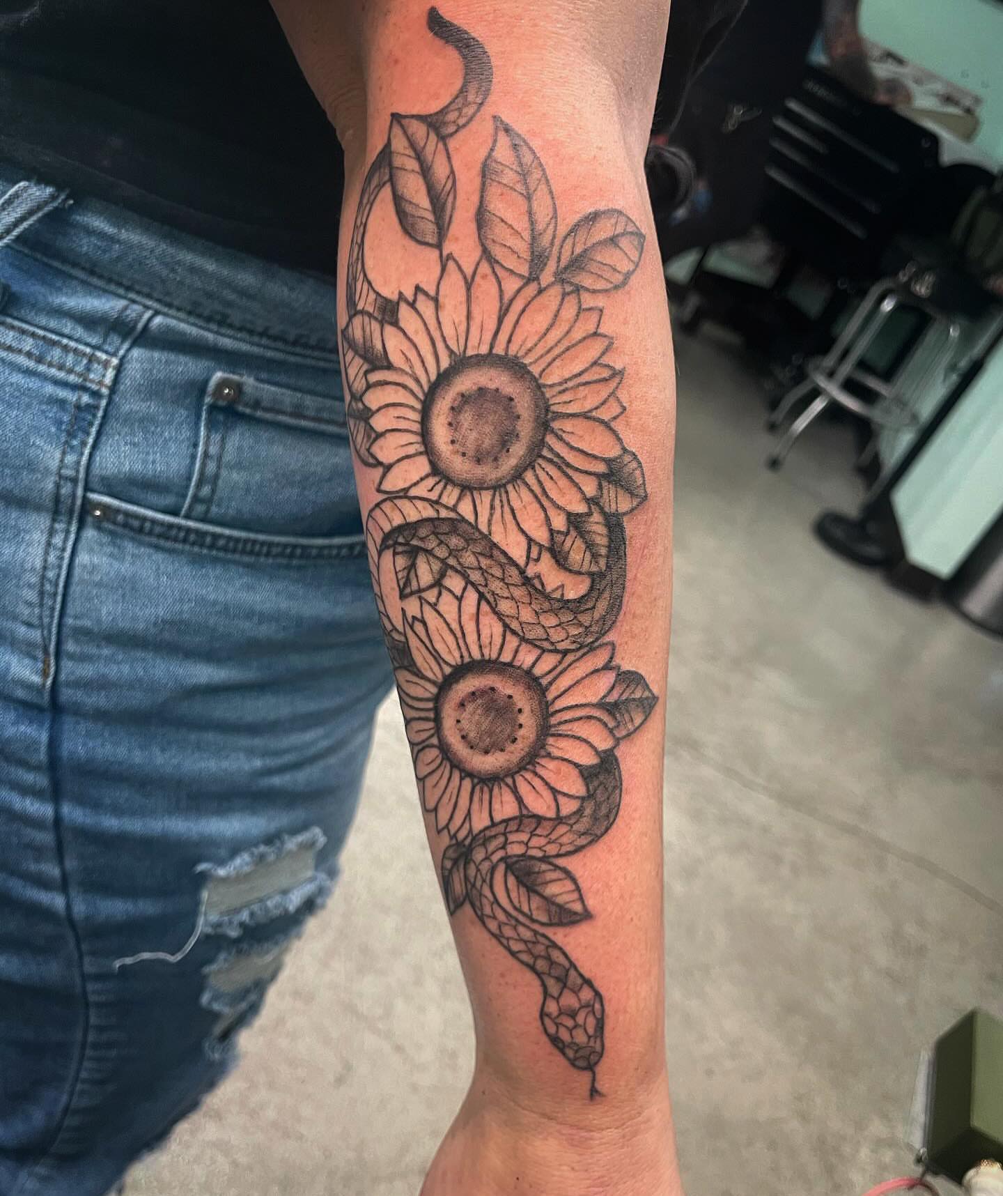 Sunflower and snake black and grey tattoo on the forearm by Logan Casimir