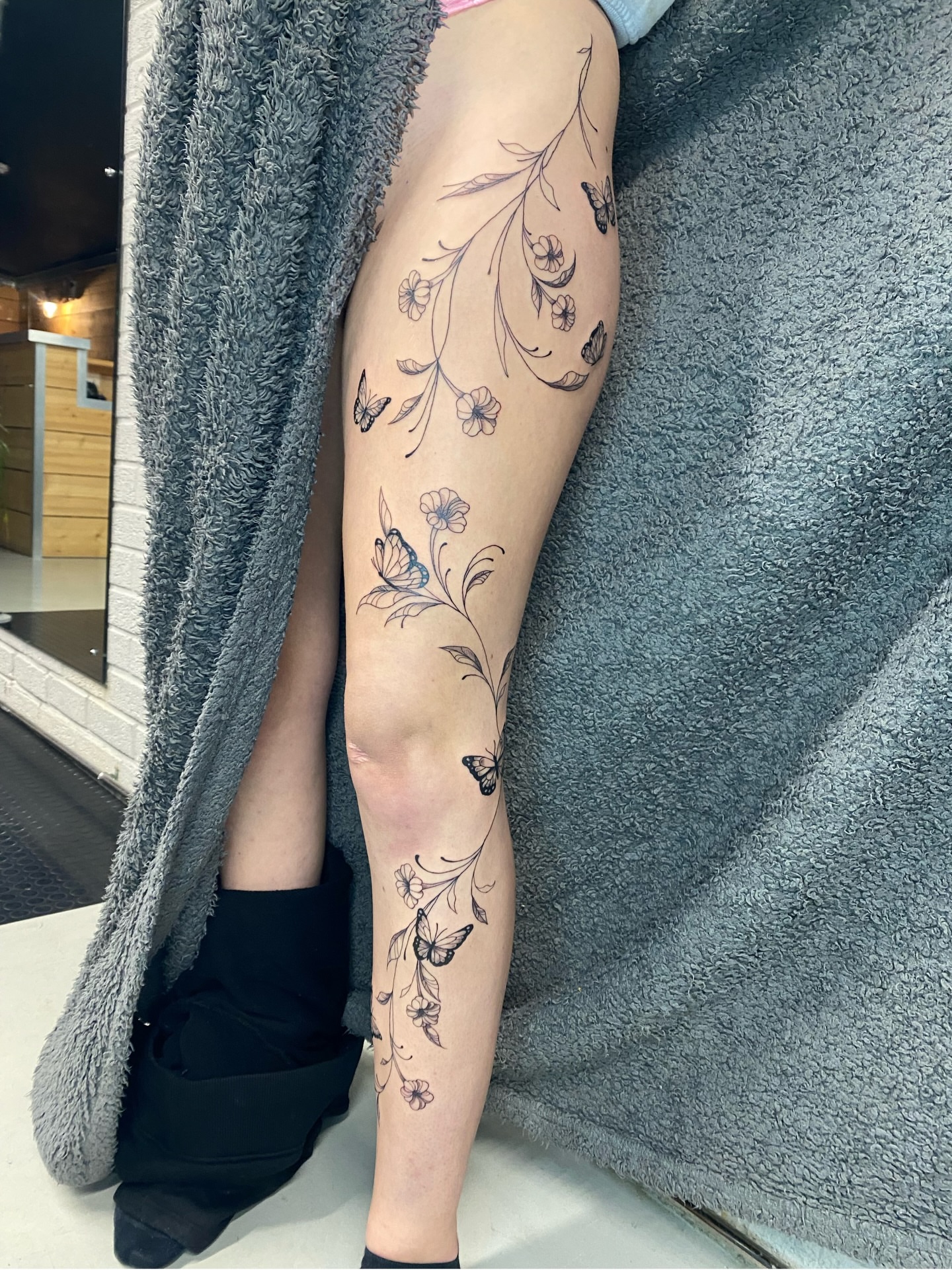 Floral vines and butterflies black and grey tattoo on the calf by Ellena Reggiani