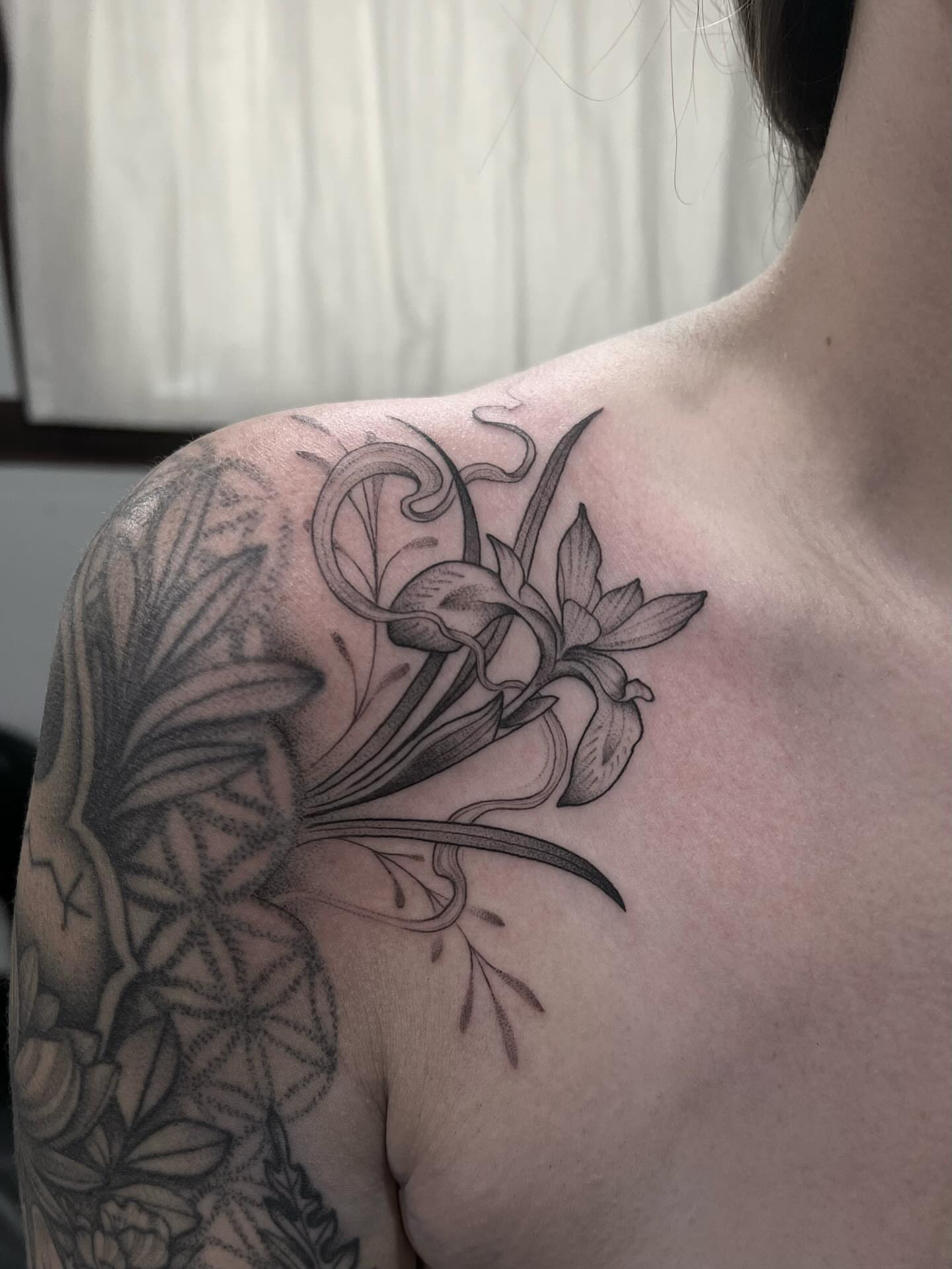 Orchid and leaves black and grey tattoo on the shoulder by Avrey Simone