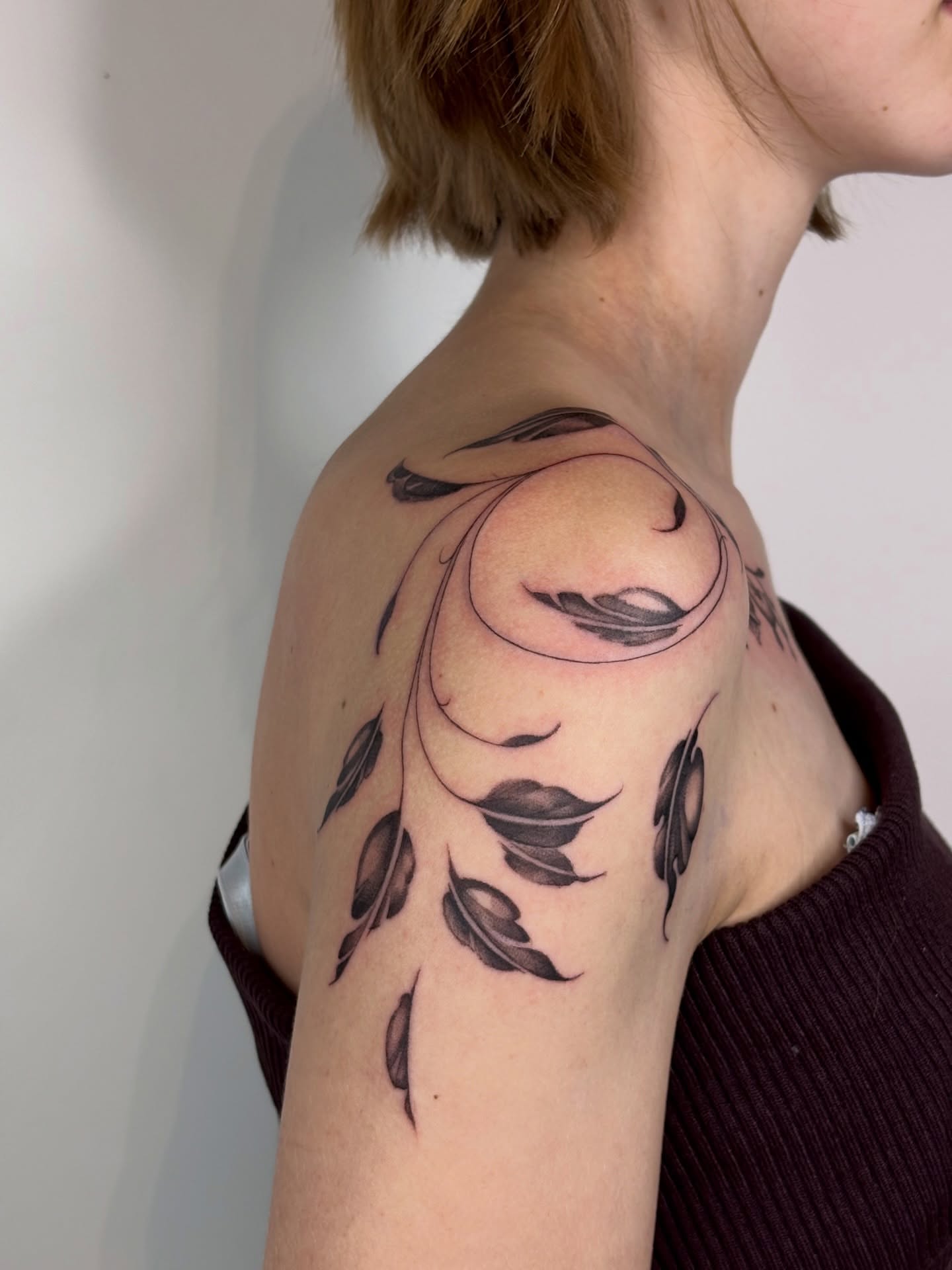 Feather black and grey tattoo on the shoulder by Dani