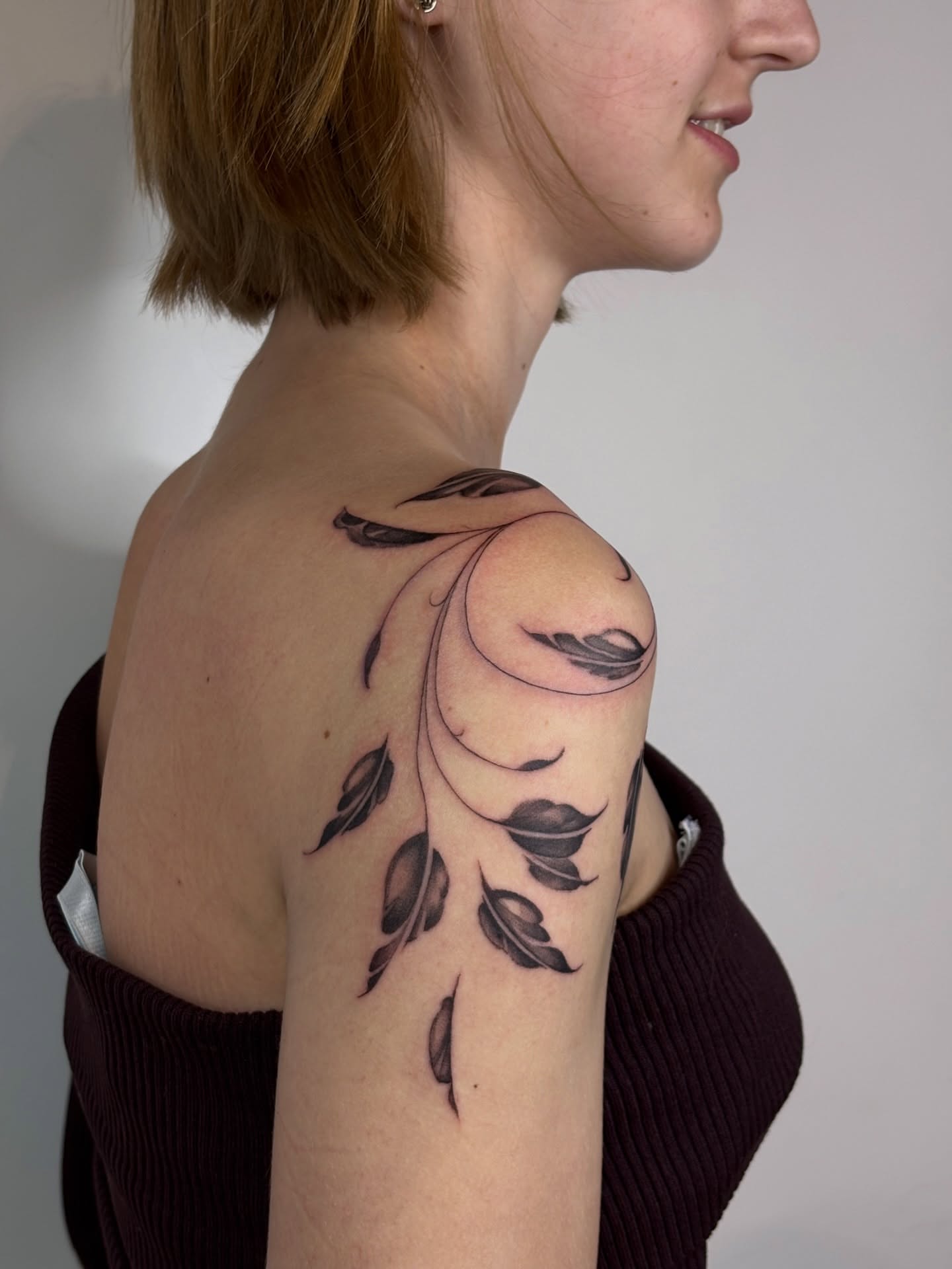 Feather black and grey tattoo on the shoulder by Dani