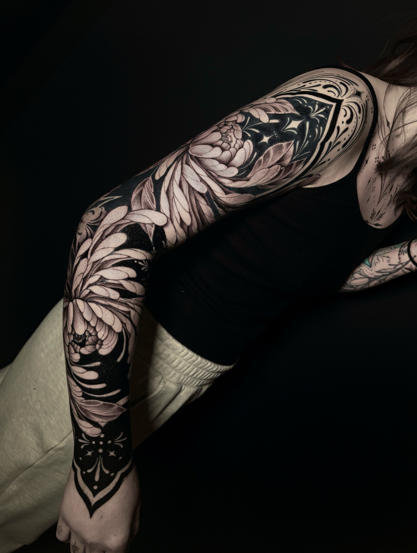 Floral and geometric ornamental tattoo on the upper arm by Fine Line Tattoo Artist