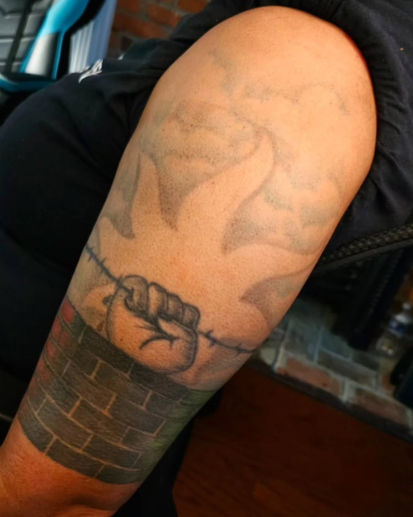 Fist breaking through brick wall black and grey tattoo on the forearm by ๐๐๐๐