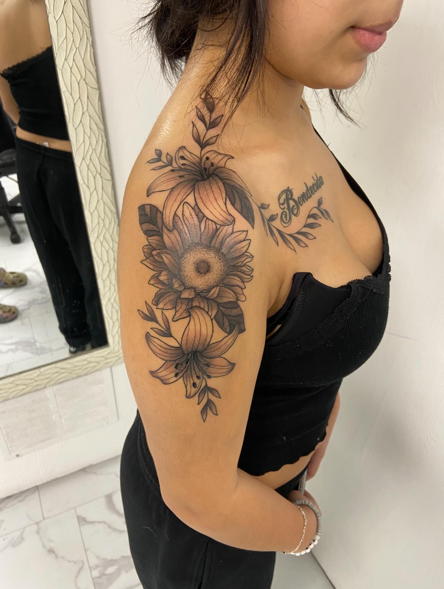 Sunflower and lily black and grey tattoo on the upper arm by Sophia
