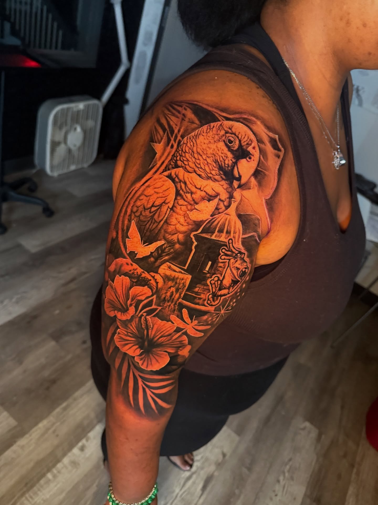 Parrot and flowers realism tattoo on the upper arm by Atlanta Tattoo Artist