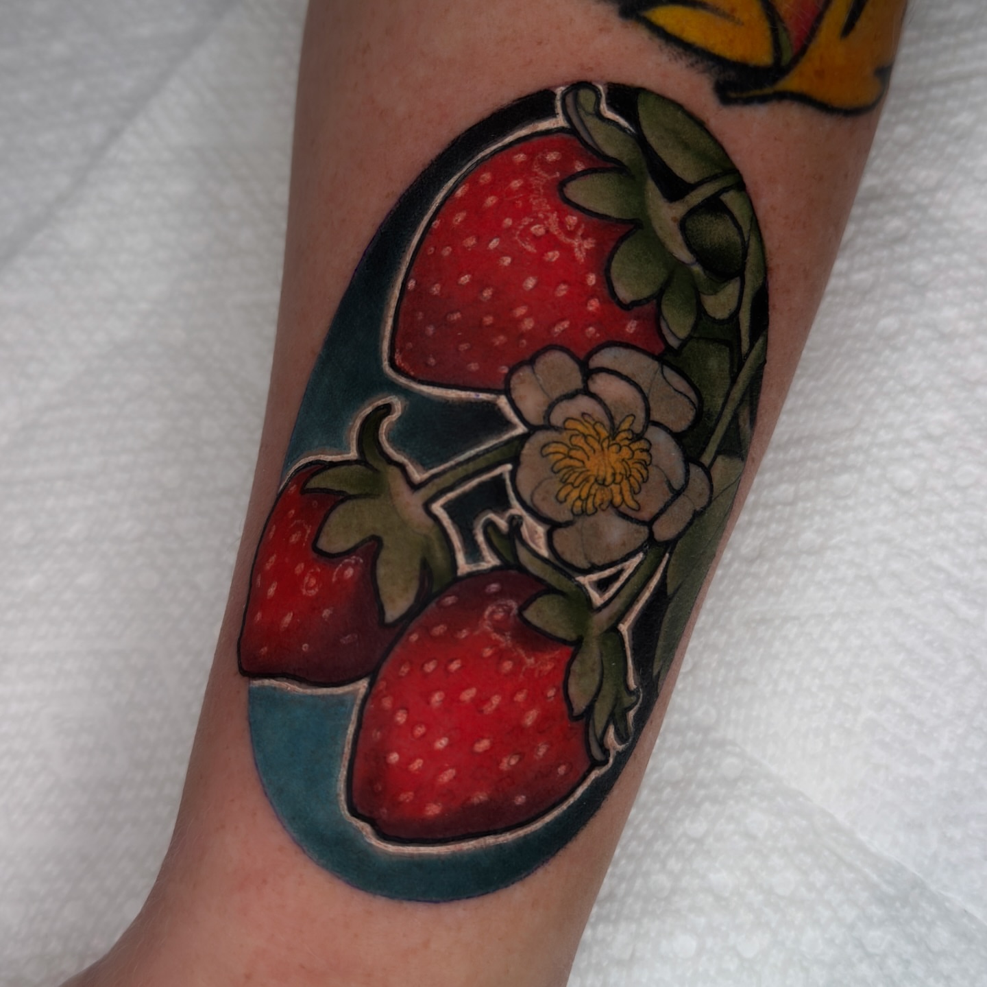 Strawberries and flower American traditional tattoo on the forearm by Golden Heart Tattoo Co