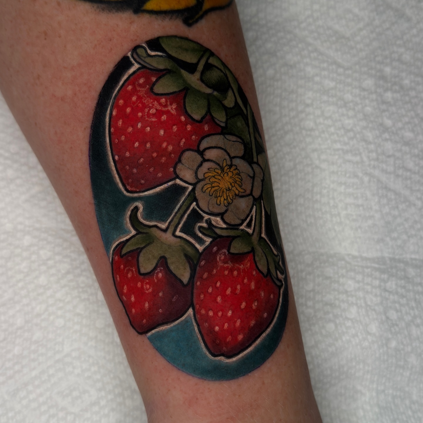 Strawberries and flower American traditional tattoo on the forearm by Golden Heart Tattoo Co