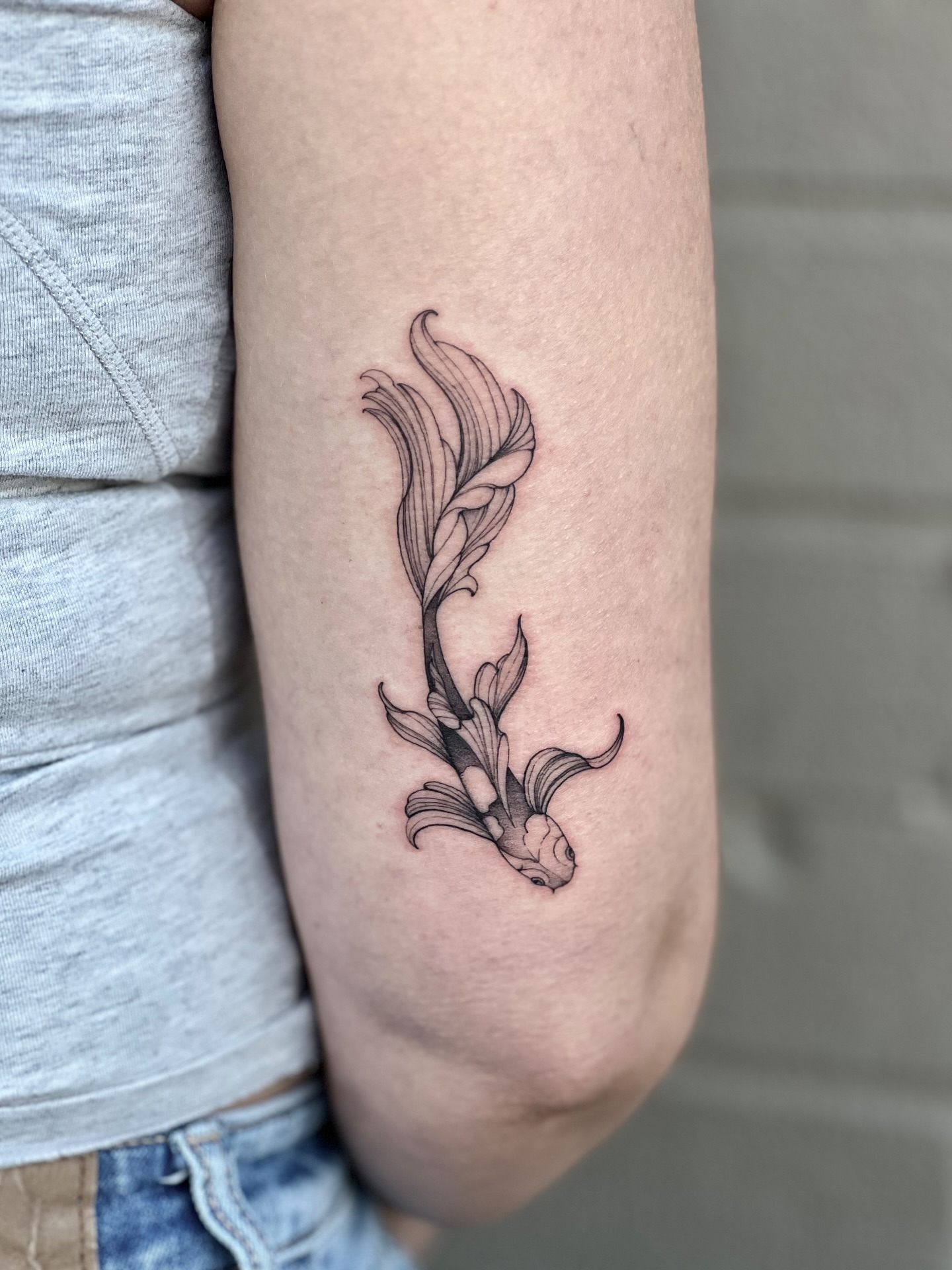 Koi fish and lotus black and grey tattoo on the forearm by Tehnaya