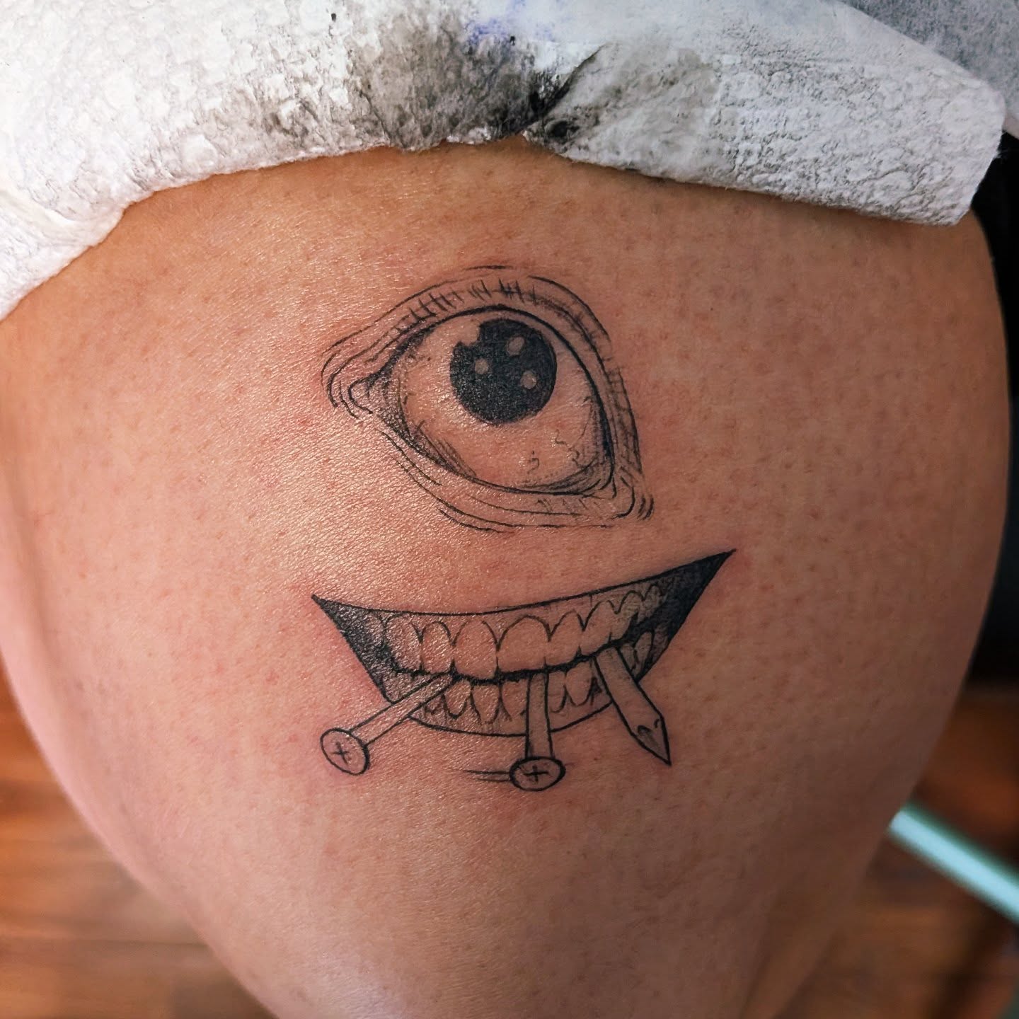 Eye and teeth dotwork tattoo on the thigh by Shannon