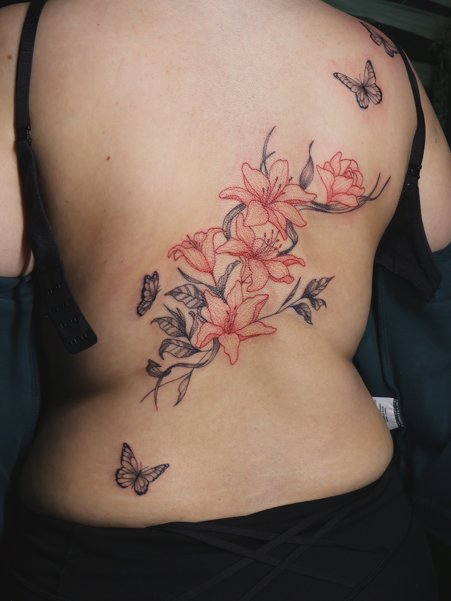 Lilies and butterflies realism tattoo on the back by 𝑭𝒊𝒏𝒆 𝑳𝒊𝒏𝒆 𝑻𝒂𝒕𝒕𝒐𝒐’𝒔