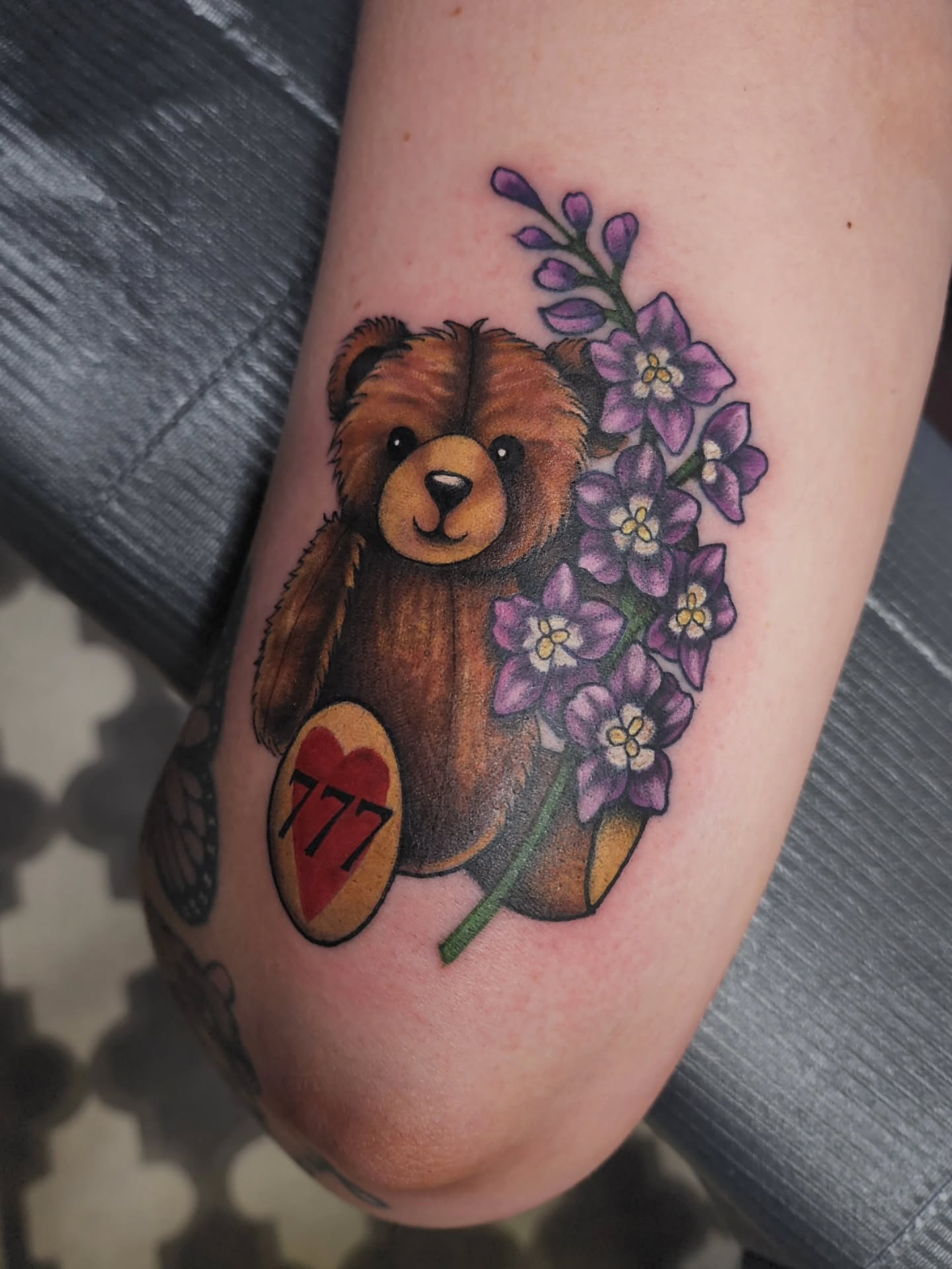 Teddy bear with flowers realism tattoo on the forearm by Shawna Goettsche