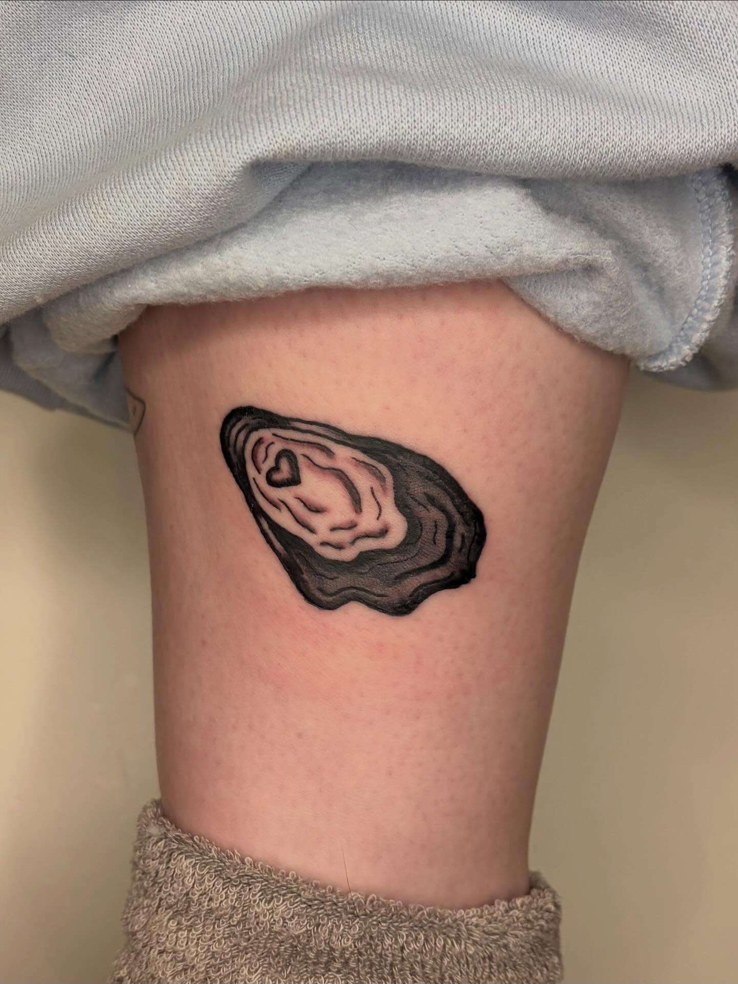 Oyster black and grey tattoo on the thigh by Fin :