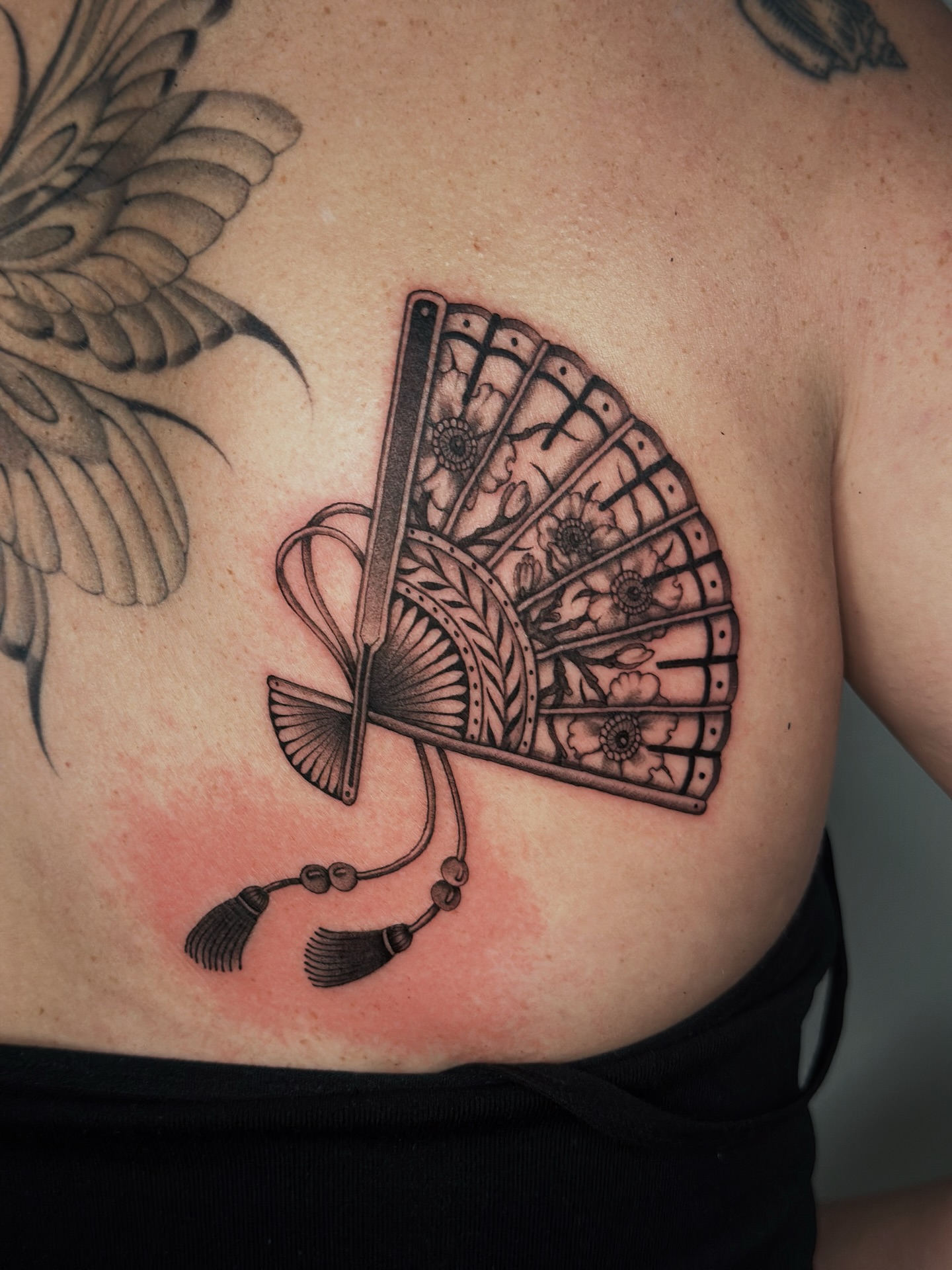 Fan black and grey tattoo on the chest by Lauryn Jenesis