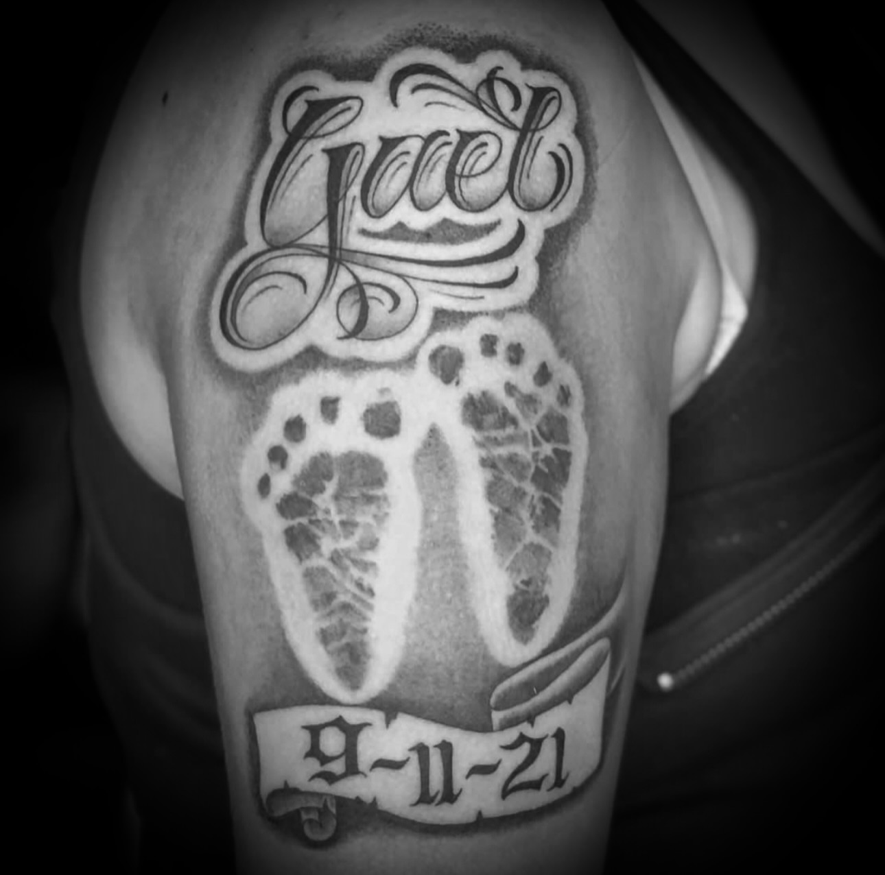 Footprint with name and date black and grey tattoo on the shoulder by Big Steve Lewis