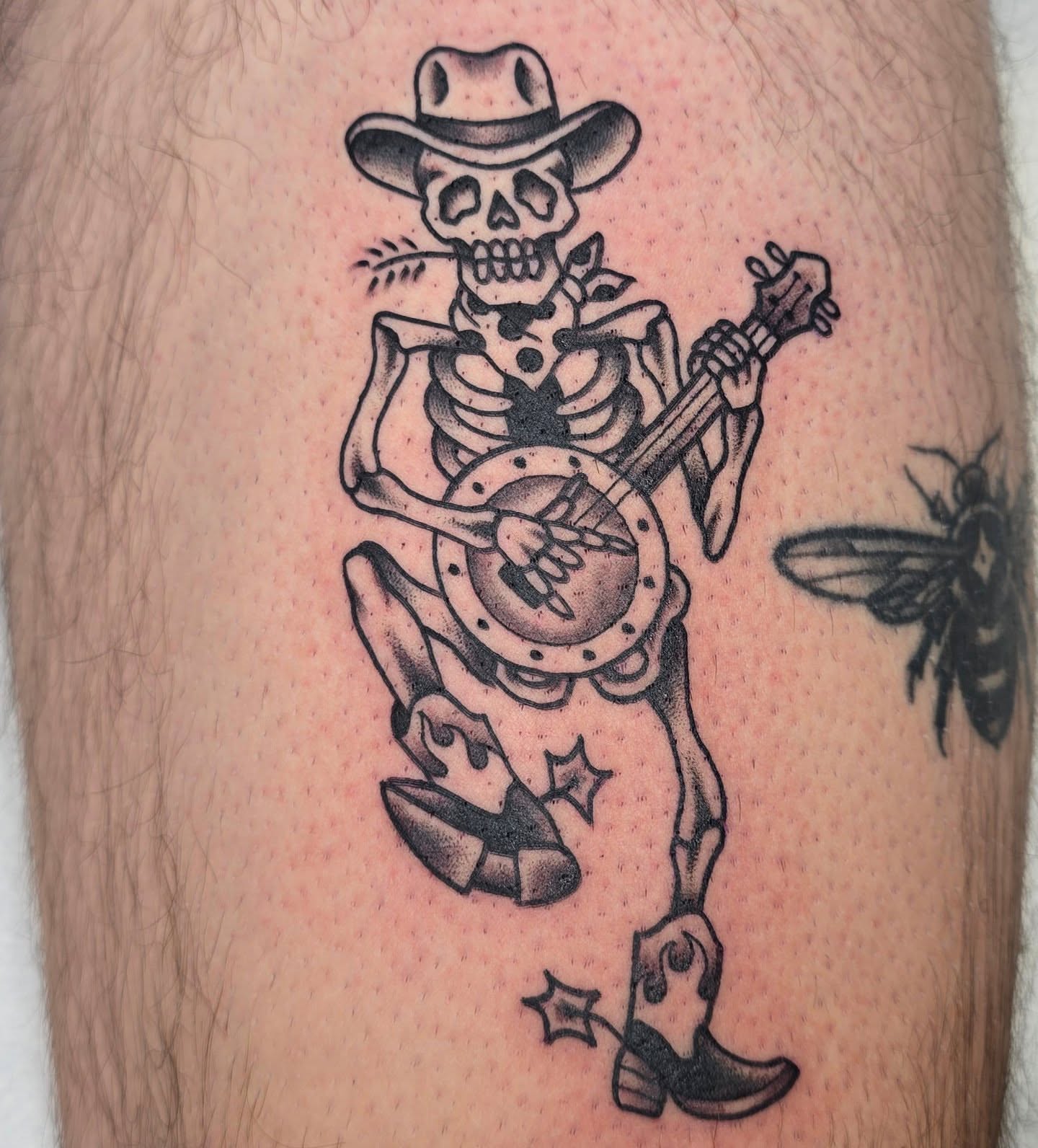 Skeleton playing banjo American traditional tattoo on the thigh by A. Teixeira, Los Angeles, California