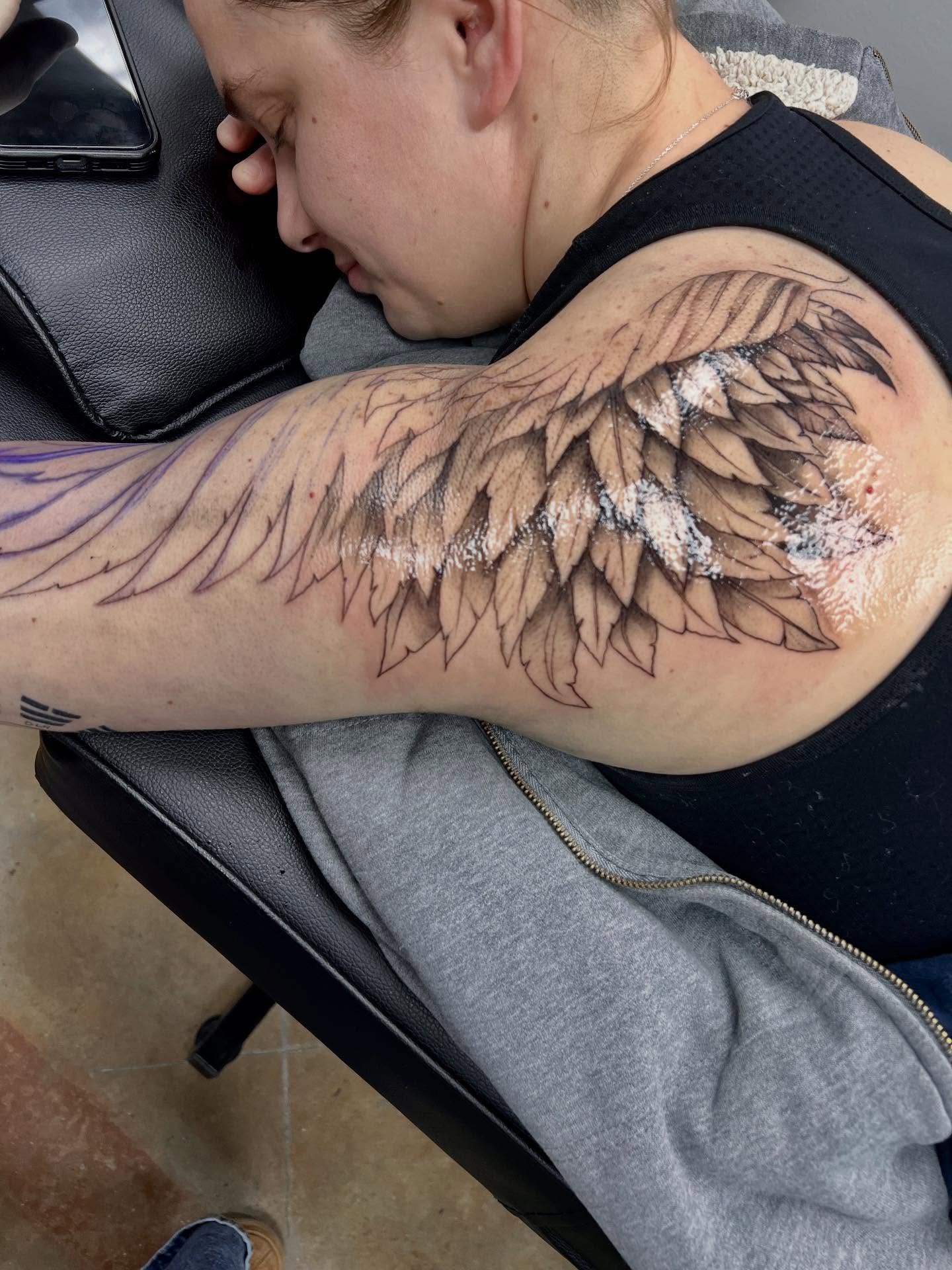 Wing black and grey tattoo on the upper arm by Rebecca Kern Tattoos