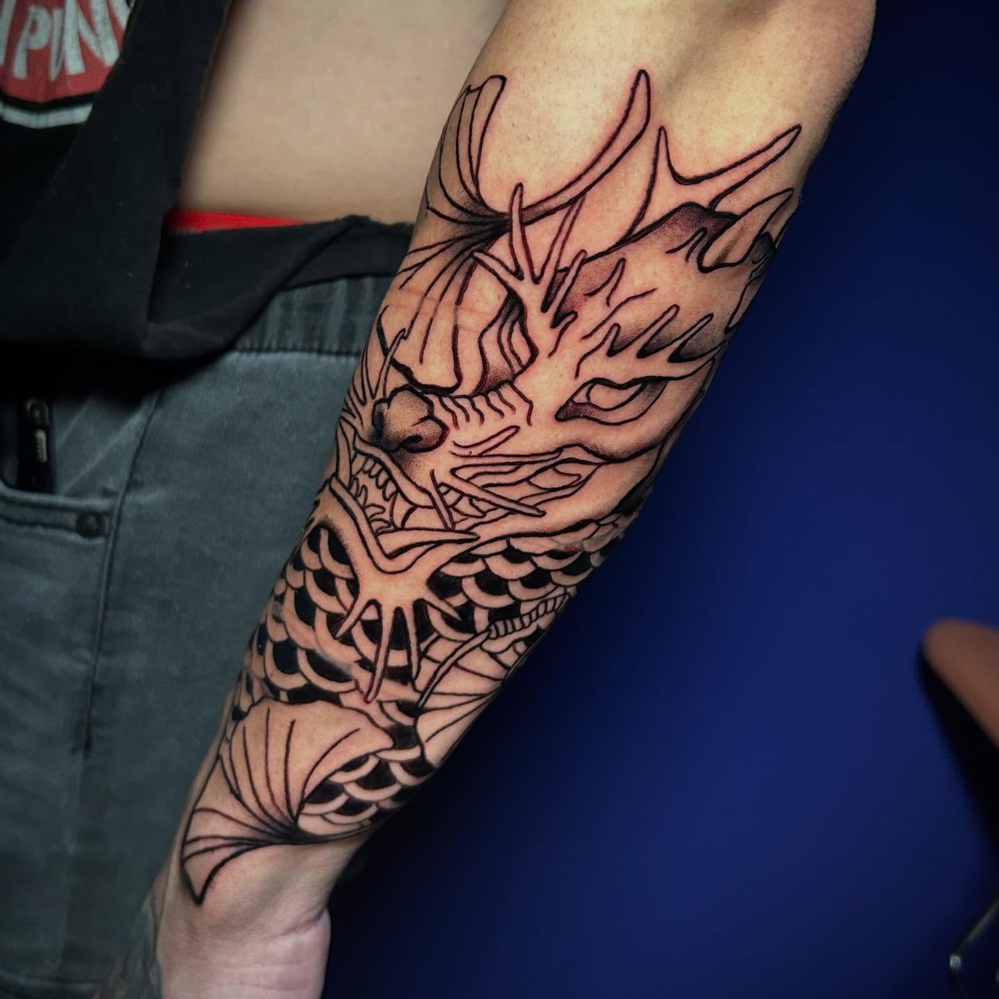 Dragon black and grey tattoo on the forearm by Adrian Michigan Tattoo Artist