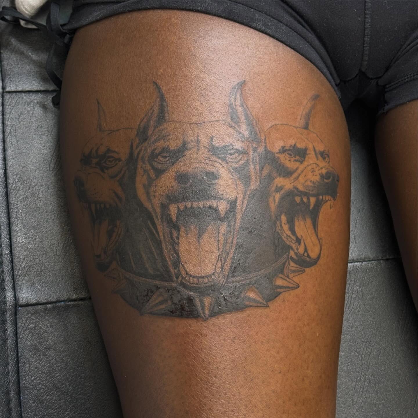 Three dogs black and grey tattoo on the thigh by Gladys L.