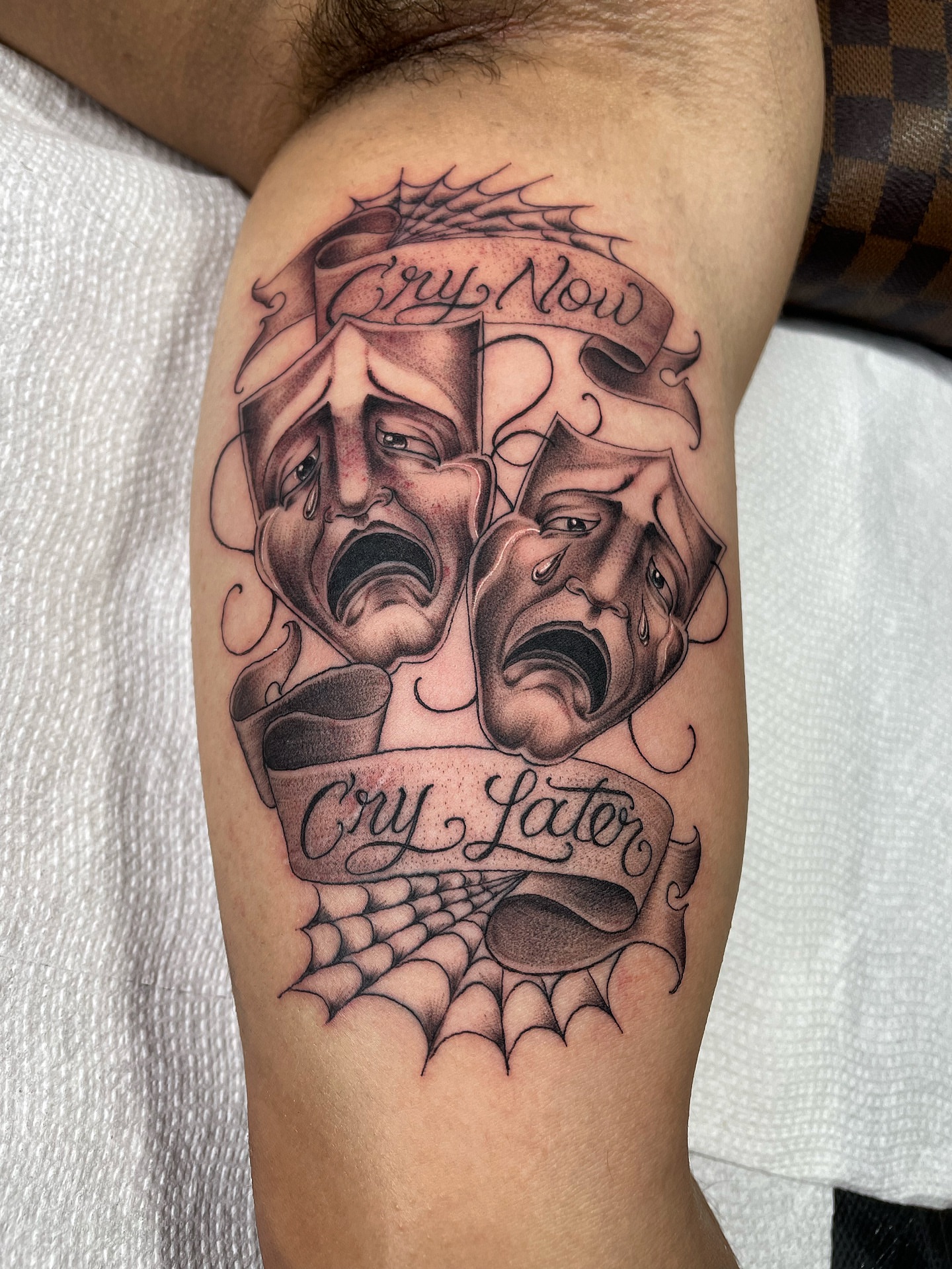 Theatrical masks black and grey tattoo on the forearm by Alex Ortiz