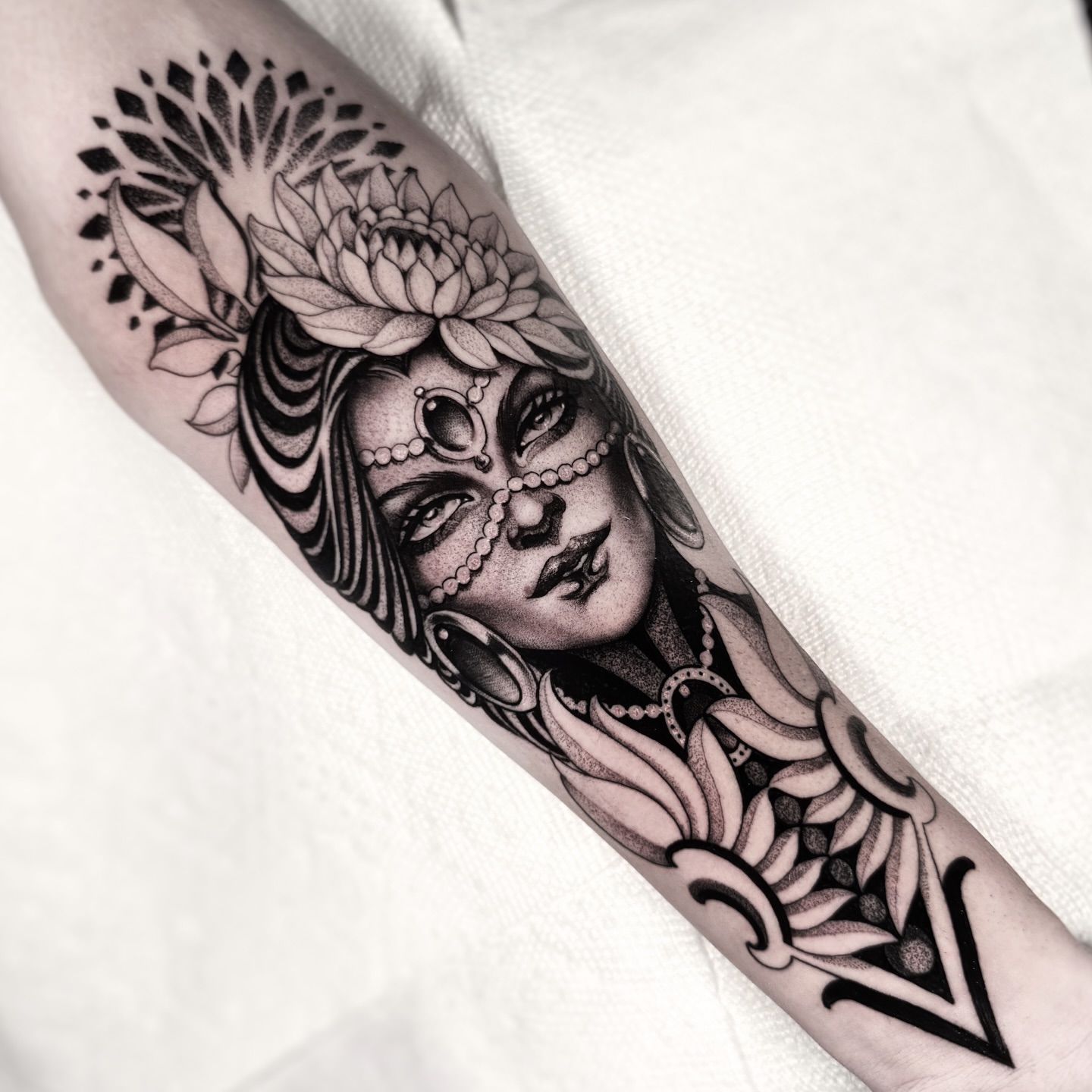 Woman with floral headdress realism tattoo on the forearm by Tommy Sisneros