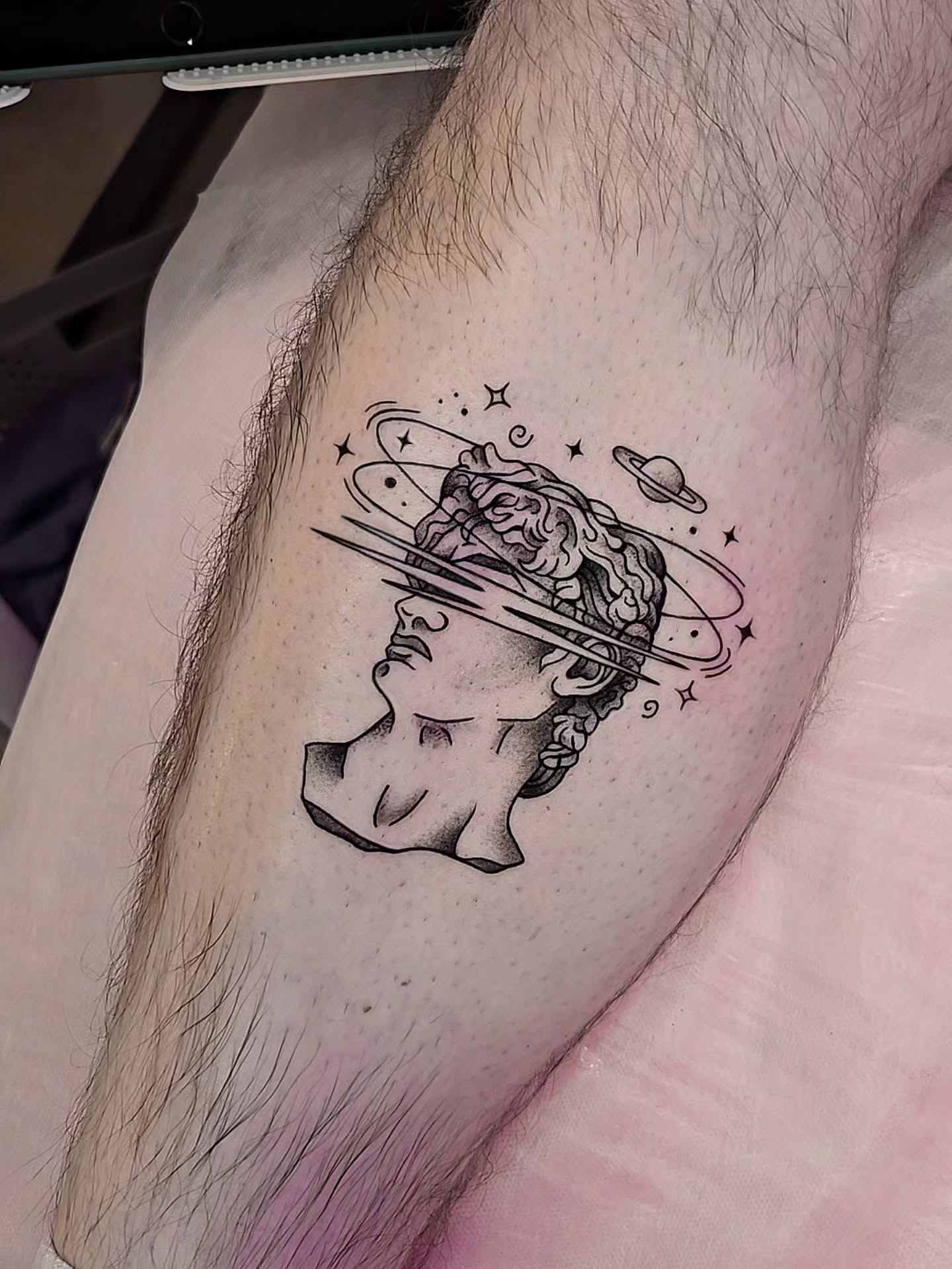 Statue head with celestial rings realism tattoo on the thigh by Kirstie Lew Tattoo