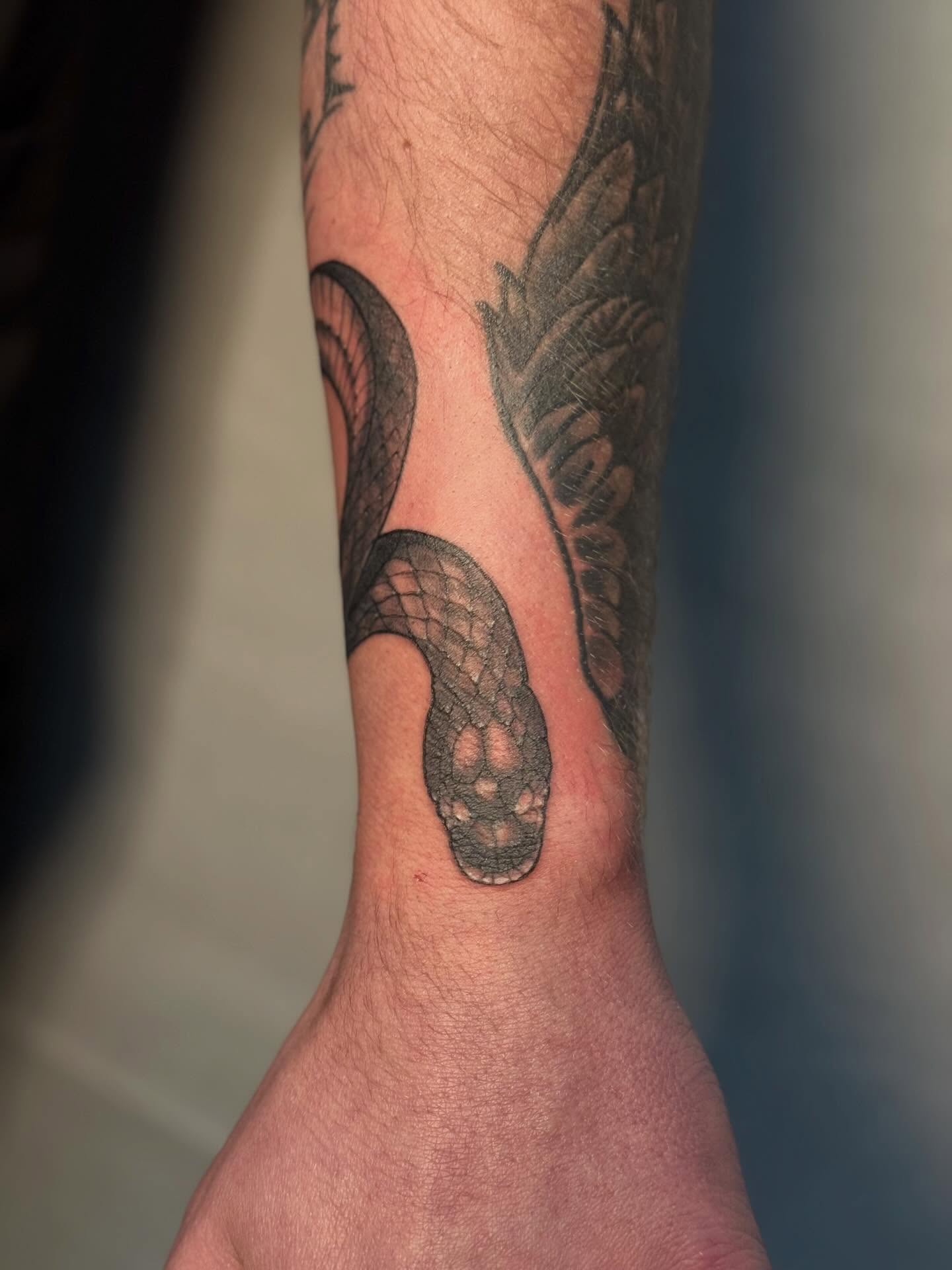 Snake black and grey tattoo on the forearm by Rachel Hanke