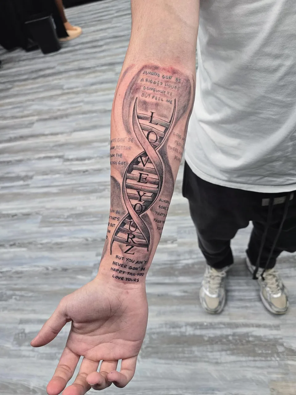 DNA helix with text black and grey tattoo on the forearm by Eldaddy