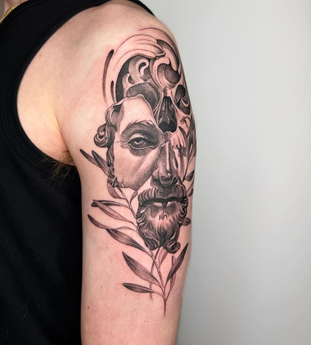 Skull and classical bust with foliage surrealism tattoo on the upper arm by Alyssa . Villela
