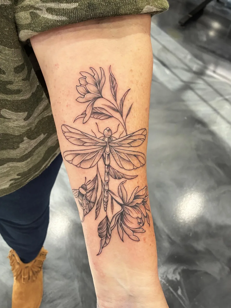 Dragonfly and flowers black and grey tattoo on the forearm by Adam Silfies